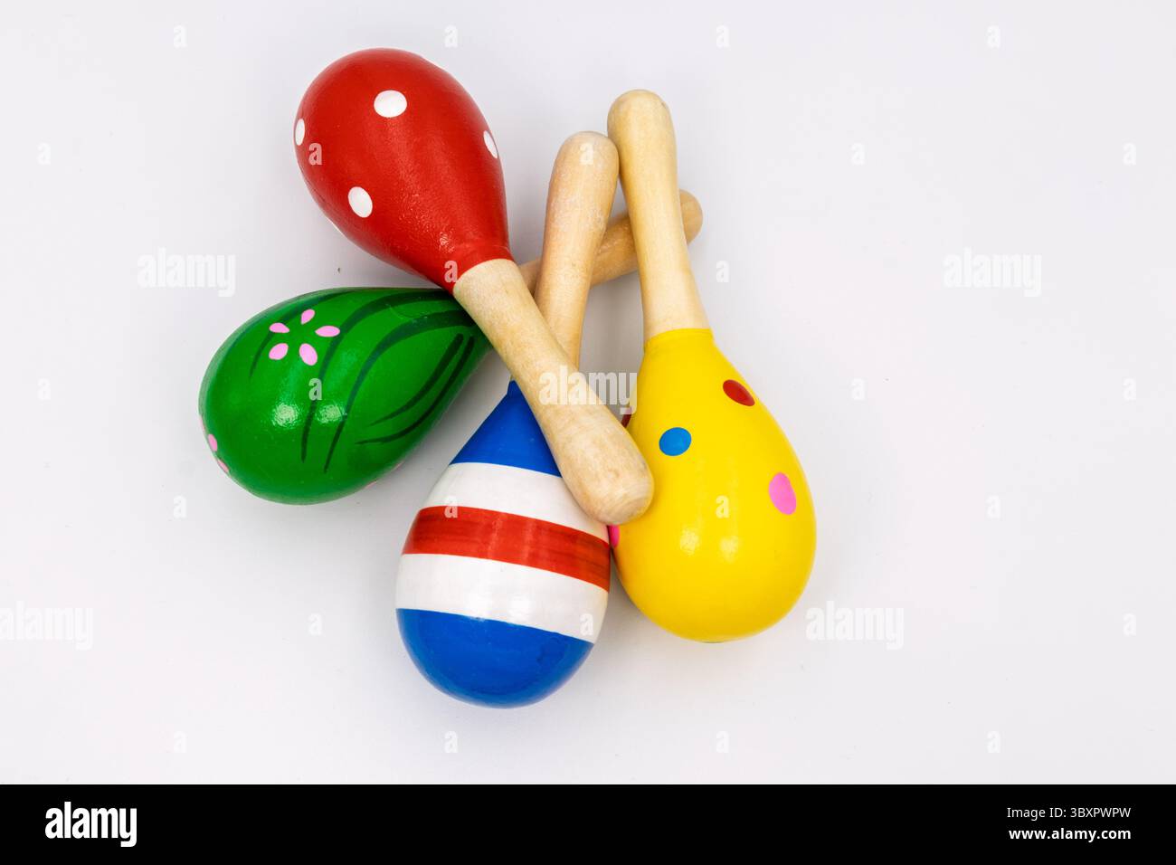 Drei lebhafte Maracas aus Holz mit verschiedenen Mustern - rot mit weißen Punkten, grün mit rosa Blumen und gelb mit farbigen Flecken - für Musi angeordnet Stockfoto