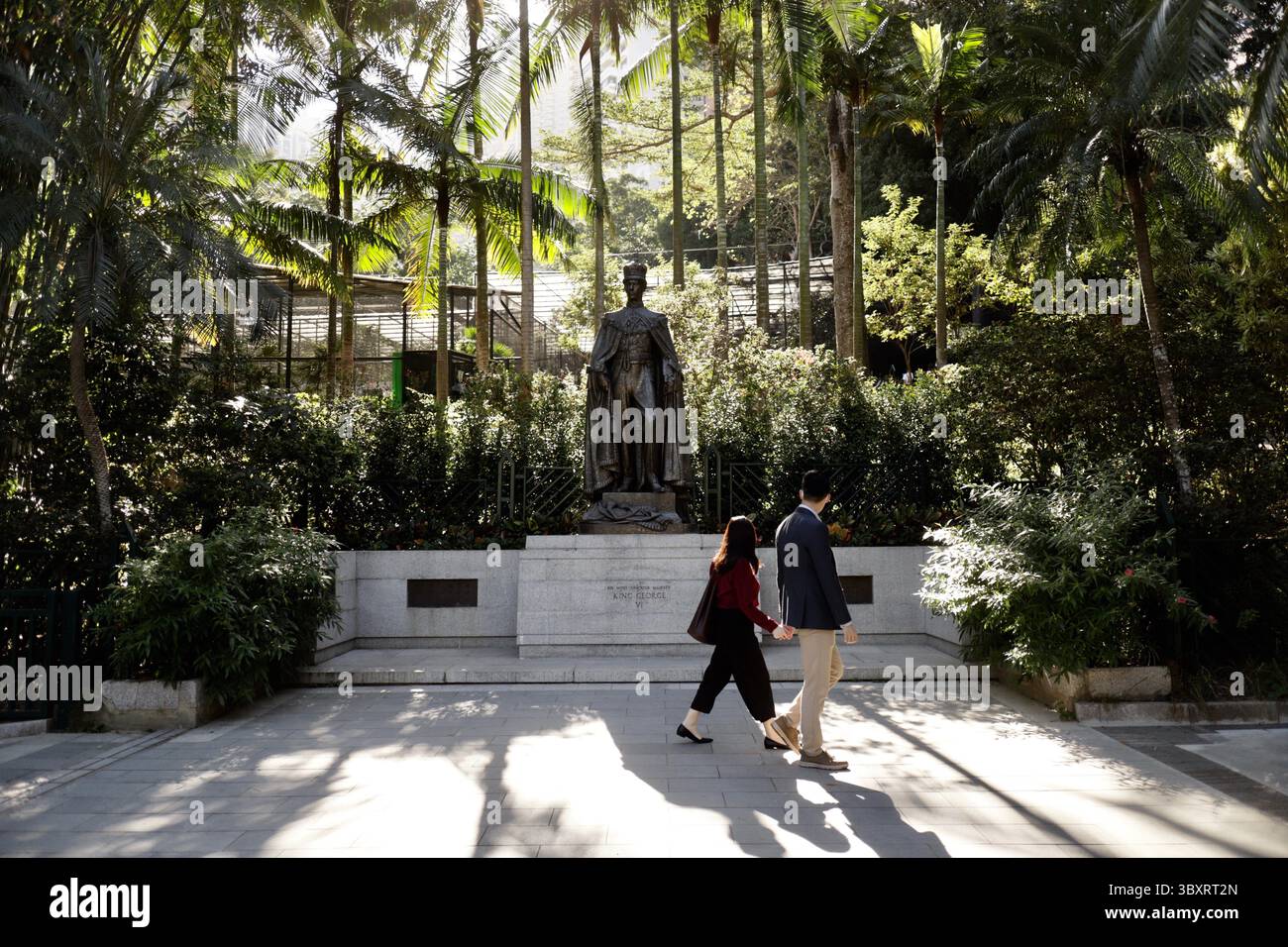3. Dezember 2021, HONGKONG, CHINA: Ein Paar, das an der Bronzestatue von König George VI. Von Großbritannien im Zoologischen & Botanischen Garten von Hong Kong vorbeigeht. Nach der ÜBERGABE Hongkongs an China im Jahr 1997 gibt es in Hongkong nur zwei Statuen der britischen Monarchie, eine Bronzestatue von Königin Victoria im Victoria Park und eine Statue von König George VI im Botanischen Garten, Central. Dies sind die letzten Symbole der britischen Kolonialvergangenheit in Hongkong unter der Herrschaft des chinesischen Kommunismus.Dez-3.2021Hong Kong.ZUMA/Liau Chung-ren (Bild: © Liau Chung-ren/ZUMA Press Wire) Stockfoto