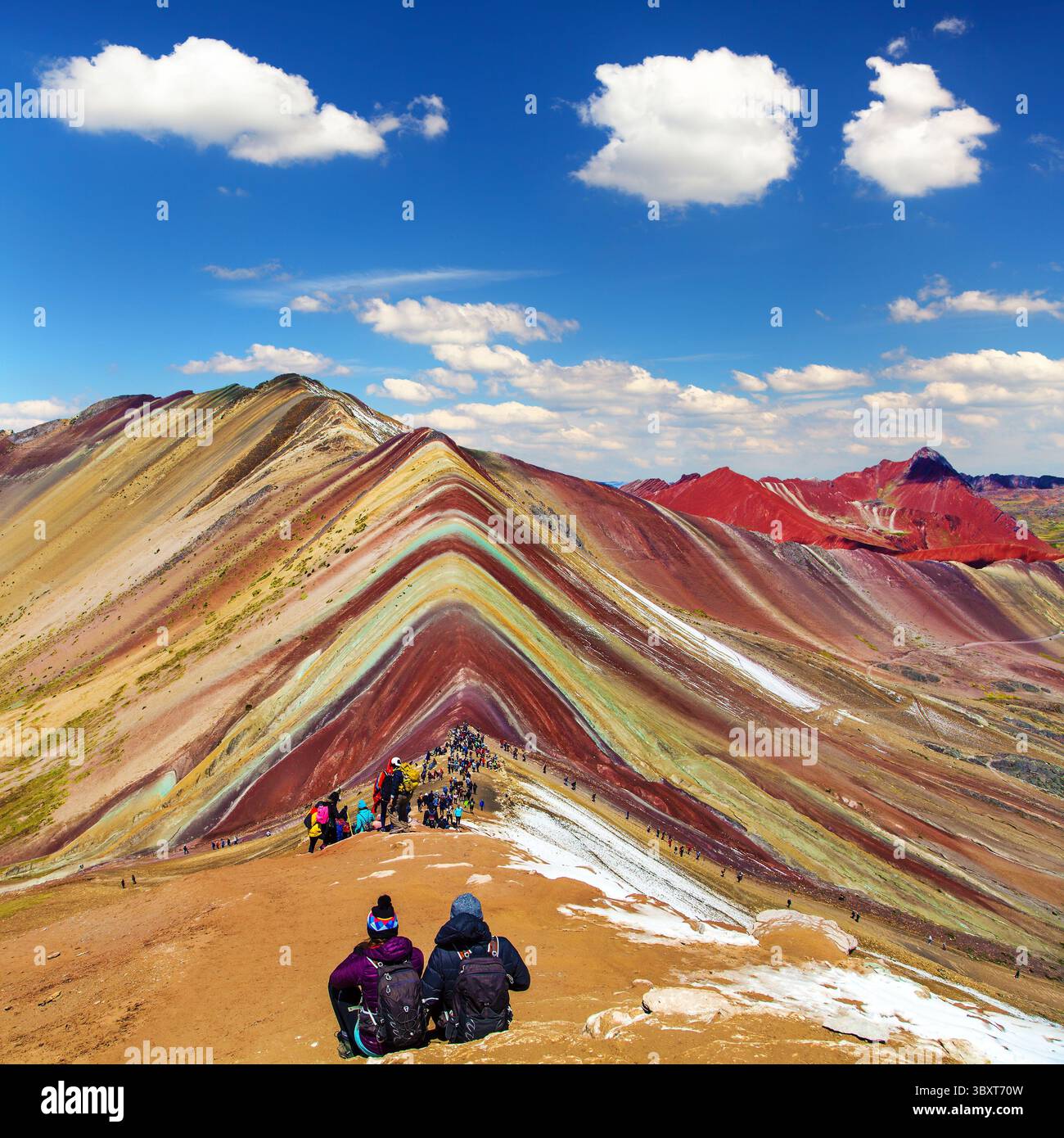 Regenbogenberge oder Vinicunca Montana de Siete Colores mit Touristen und wunderschönen Wolken am Himmel, Cuzco Region in Peru, peruanische Anden, Panorama mou Stockfoto