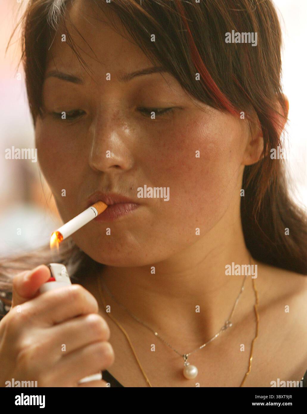 14. Juli 2006, PEKING, CHINA: Eine Chinesin zündet eine Zigarette in einem Café in der Innenstadt von Peking an, 14. Juli 2006. Die chinesische Regierung hat strengere Maßnahmen zur Eindämmung des Rauchens auf dem weltweit größten Zigarettenmarkt gefordert, wobei Frauen und Teenager immer mehr an Gewohnheit gewinnen. Einem kürzlich veröffentlichten Bericht zufolge gibt es in China schätzungsweise 320 Millionen Raucher, die zweifellos den größten Nunmber der Opfer in einem Land mit wenig Gesundheitsoptionen produzieren werden. (Bild: © Stephen Shaver/ZUMA Press Wire) Stockfoto