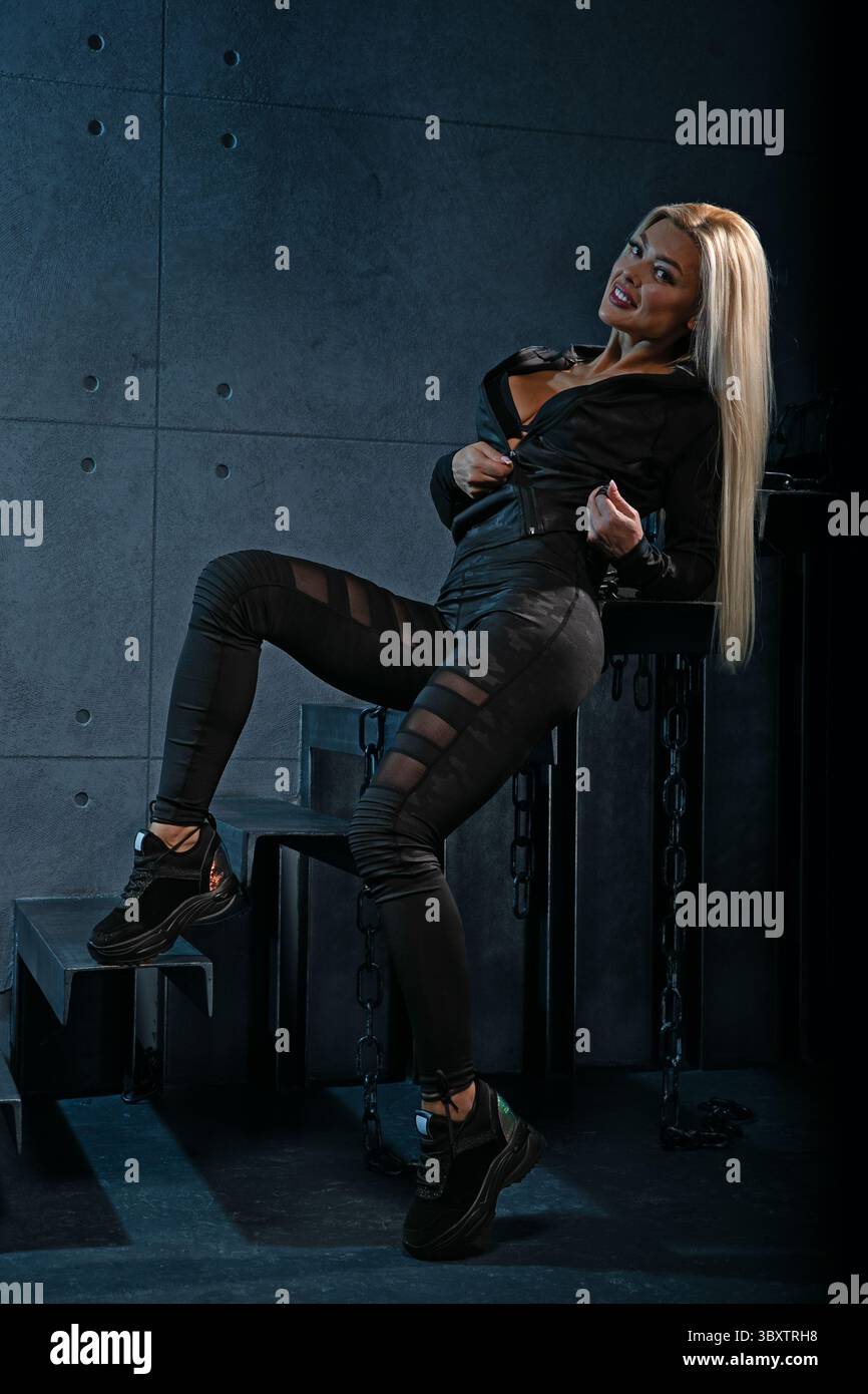 Die blonde Athletin zeigt ihre Stärke und ihren Stil, während sie in schlanken, sportlichen Kleidungsstücken posiert. Ihr selbstbewusster, dynamischer Ausdruck unterstreicht ihre Hingabe und ihre Fitness-Performance Stockfoto
