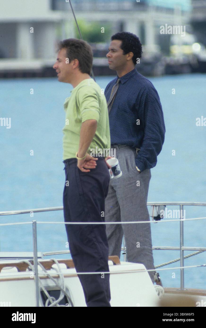 Circa 1984, Miami, Florida, USA: DON JOHNSON mit PHILIP MICHAEL THOMAS während der Dreharbeiten von Miami Vice. Miami Vice war eine US-amerikanische Krimi-Serie mit Don Johnson als James „Sonny“ Crockett und Philip Michael Thomas als Ricardo „Rico“ Tubbs, zwei Detektive des Metro-Dade Police Department, die Undercover in Miami arbeiten. (Bild: © Stan Gelberg/ZUMA Press Wire) Stockfoto