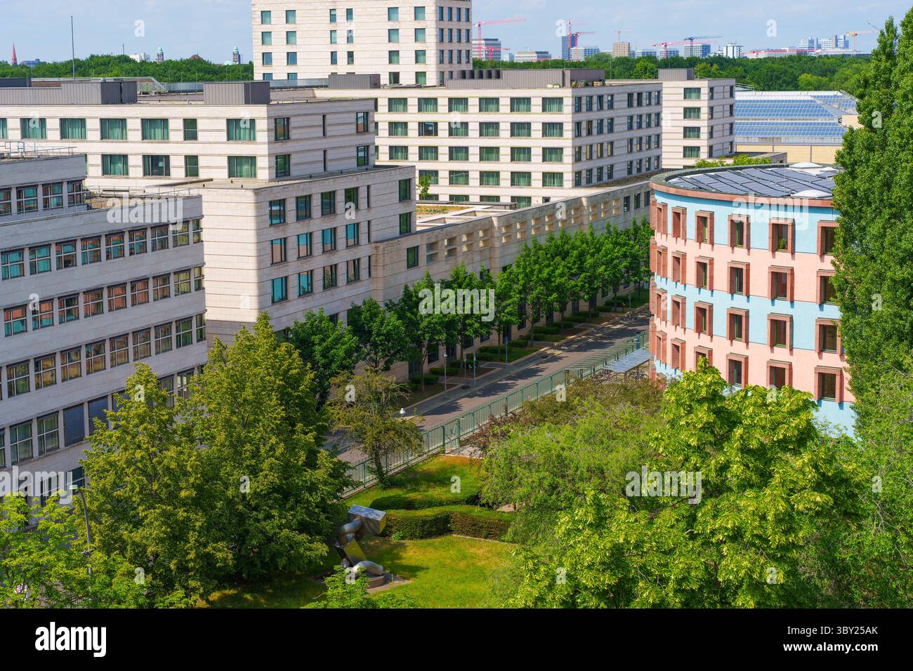 Aus der Vogelperspektive zeitgenössische Wohnhäuser in Berlin, die Grünflächen und architektonische Vielfalt unter einem hellblauen Himmel zeigen. Stockfoto