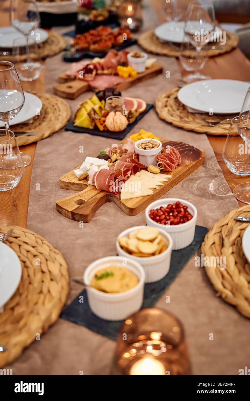 Eine elegante Wurstplatte gefüllt mit verschiedenen Käsesorten, Aufschnitt und Früchten, wunderschön auf einem rustikalen Tisch angeordnet, perfekt für einen Gourmet-di Stockfoto