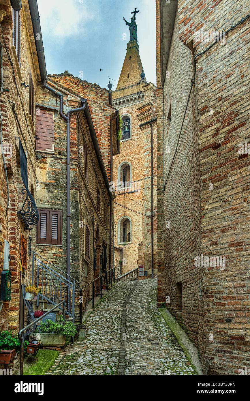 Eine mittelalterliche Straße, die von Backsteinhäusern gesäumt ist, führt zur Kathedrale der Heiligen Gregor und Margarete in Ripatransone. Ripatransone, Ascoli Piceno, Marken Stockfoto