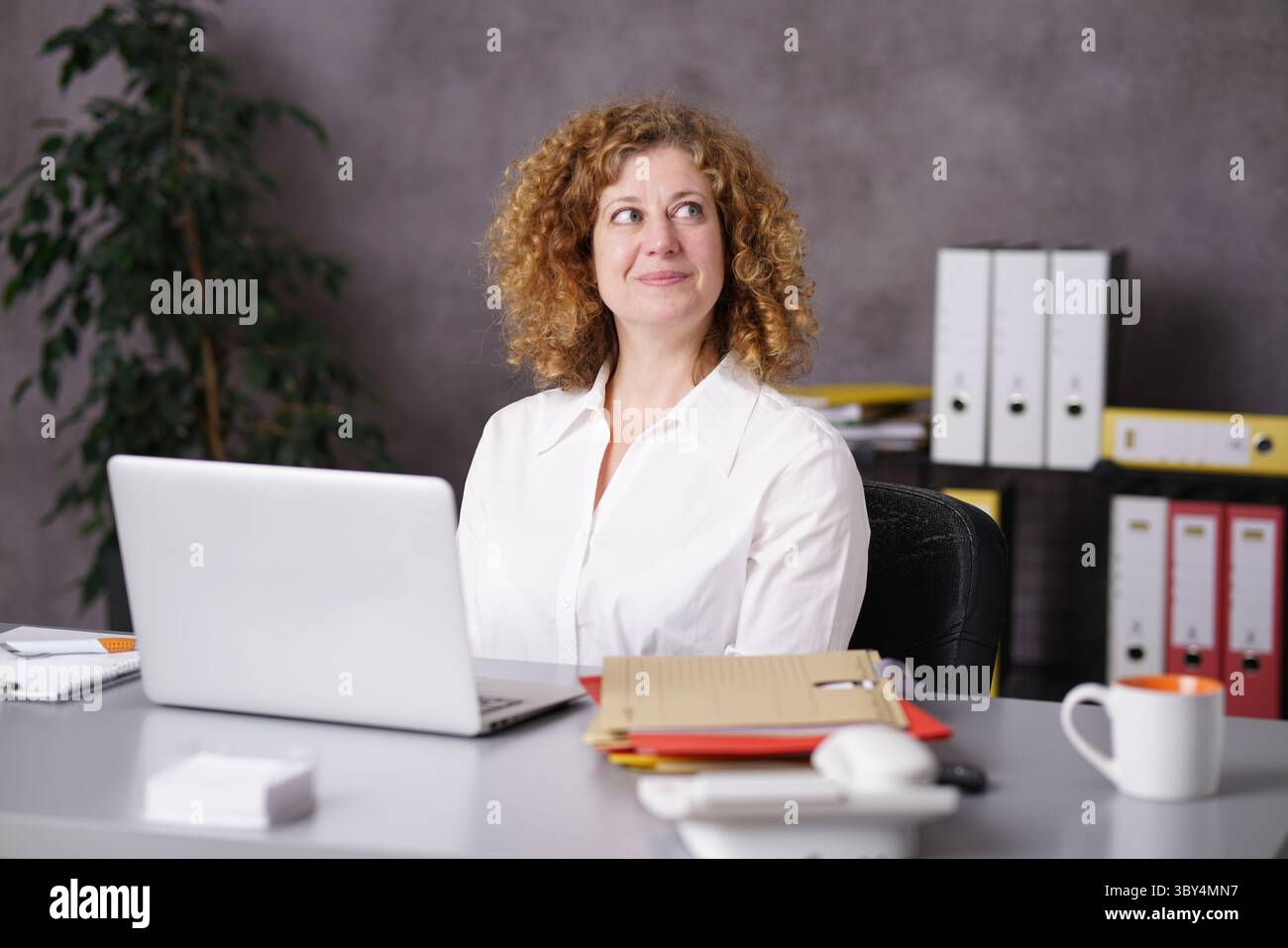 Der Sekretär sitzt am Schreibtisch und schaut in die Luft Stockfoto