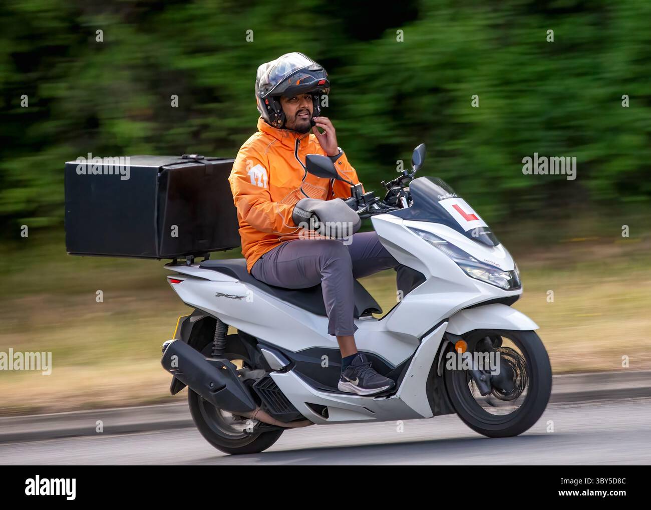 Milton Keynes, Bucks, Großbritannien - 17. Juli 2025: Just Eat Lieferfahrer mit einem 2022 Honda WW 125 Roller auf einer britischen Straße Stockfoto