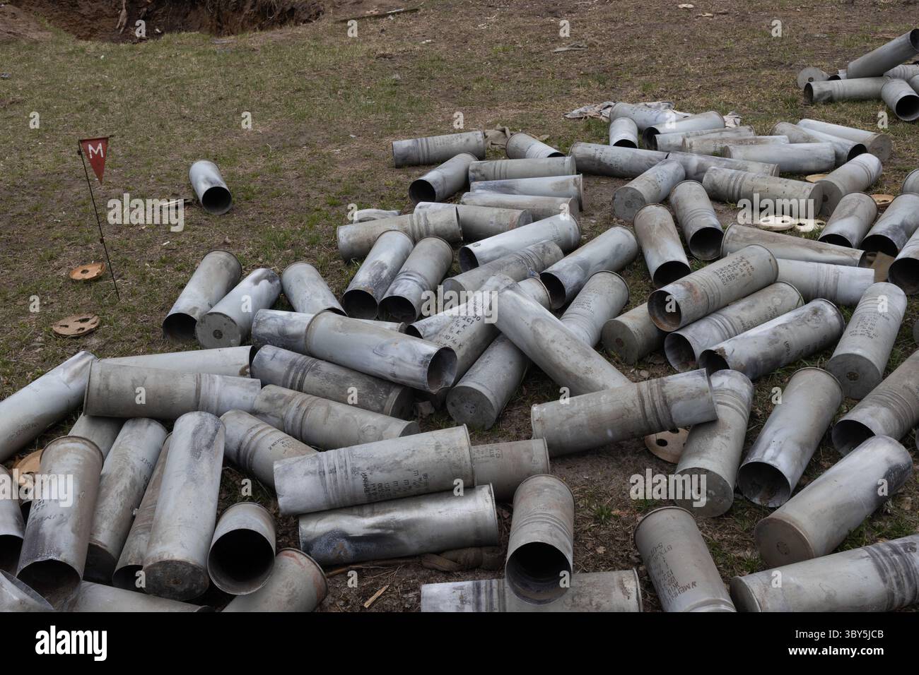 Verlassene Muschelhüllen säumen ein trostloses Schlachtfeld in der vom Krieg zerrütteten ukraine, unterbrochen von einer einsamen roten Flagge mit einem "m", eine deutliche Erinnerung an den anhaltenden Konflikt. 5. April 2022 Stockfoto