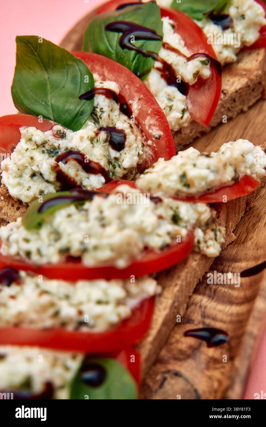 Eine frisch zubereitete Bruschetta mit cremigem Ricotta, saftigen Tomaten, Basilikumblättern und balsamischem Nieseln auf rustikalem Brot, das einen lebendigen und g-Ton bietet Stockfoto