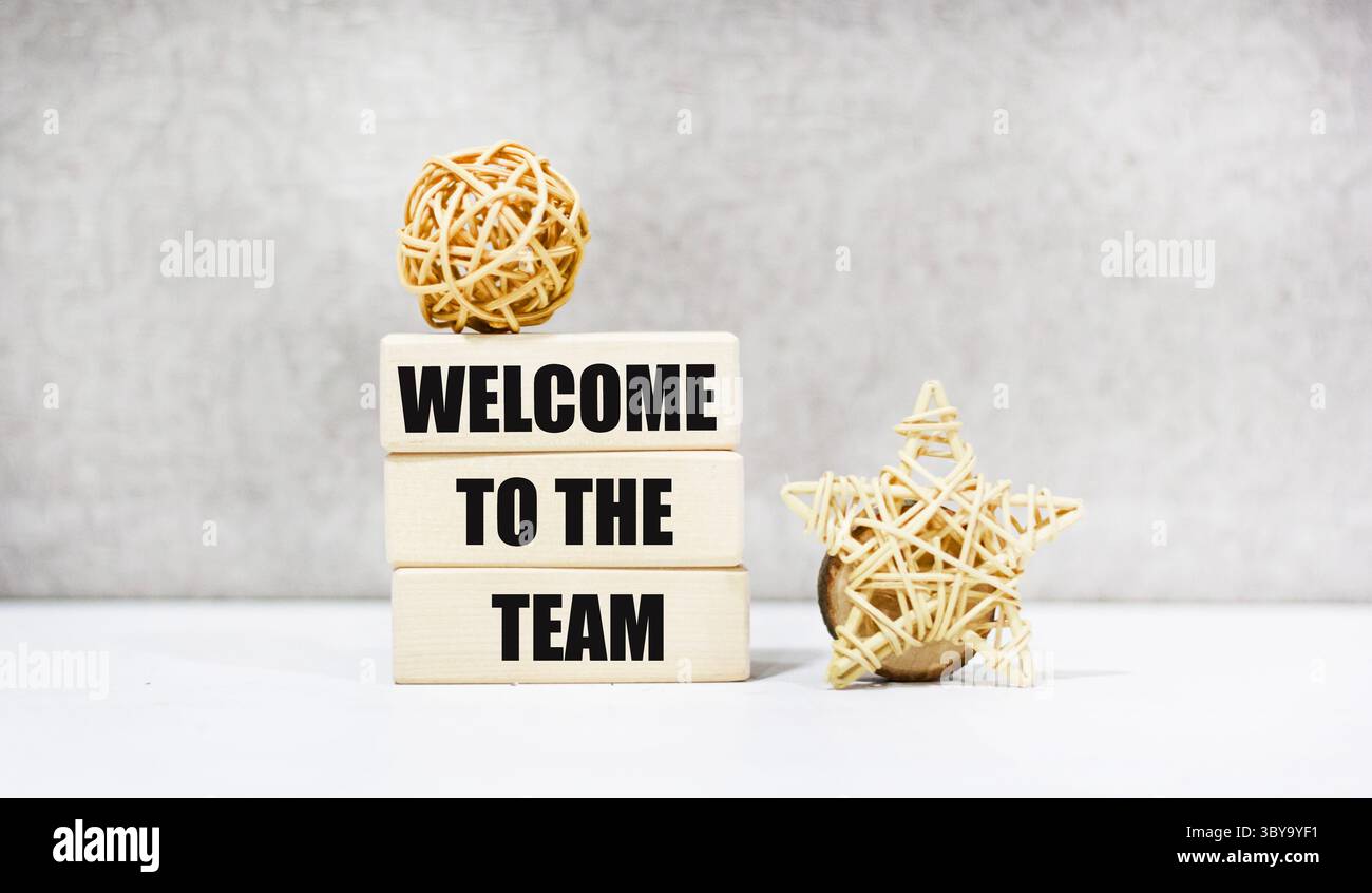 Das Symbol „Willkommen in unserem Team“ auf den Holzblöcken. Der Hintergrund ist grau. Stockfoto