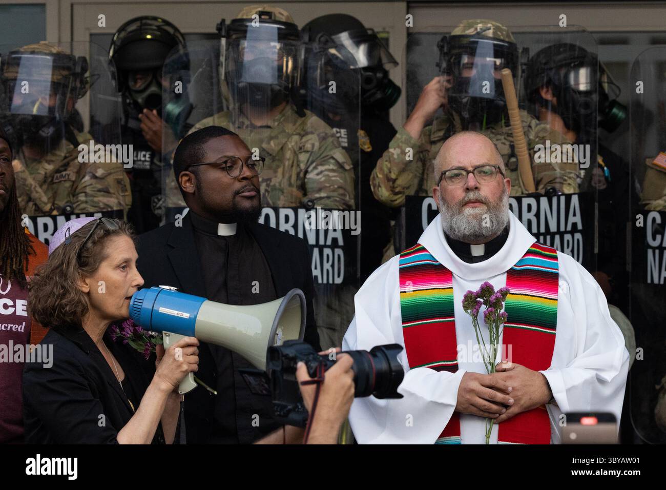 Los Angeles, Kalifornien, USA. Juni 2025. Pater Brendan Busse (R) schließt sich den Geistlichen VON LA während eines ICE-Einwanderungsprotests an, während Mitglieder der California National Guard am 10. Juni 2025 eine Perimeter am Los Angeles Street Federal Building in Los Angeles, KALIFORNIEN, halten. (Credit Image: © Jonathan Alcorn/ZUMA Press Wire) NUR REDAKTIONELLE VERWENDUNG! Nicht für kommerzielle ZWECKE! Stockfoto