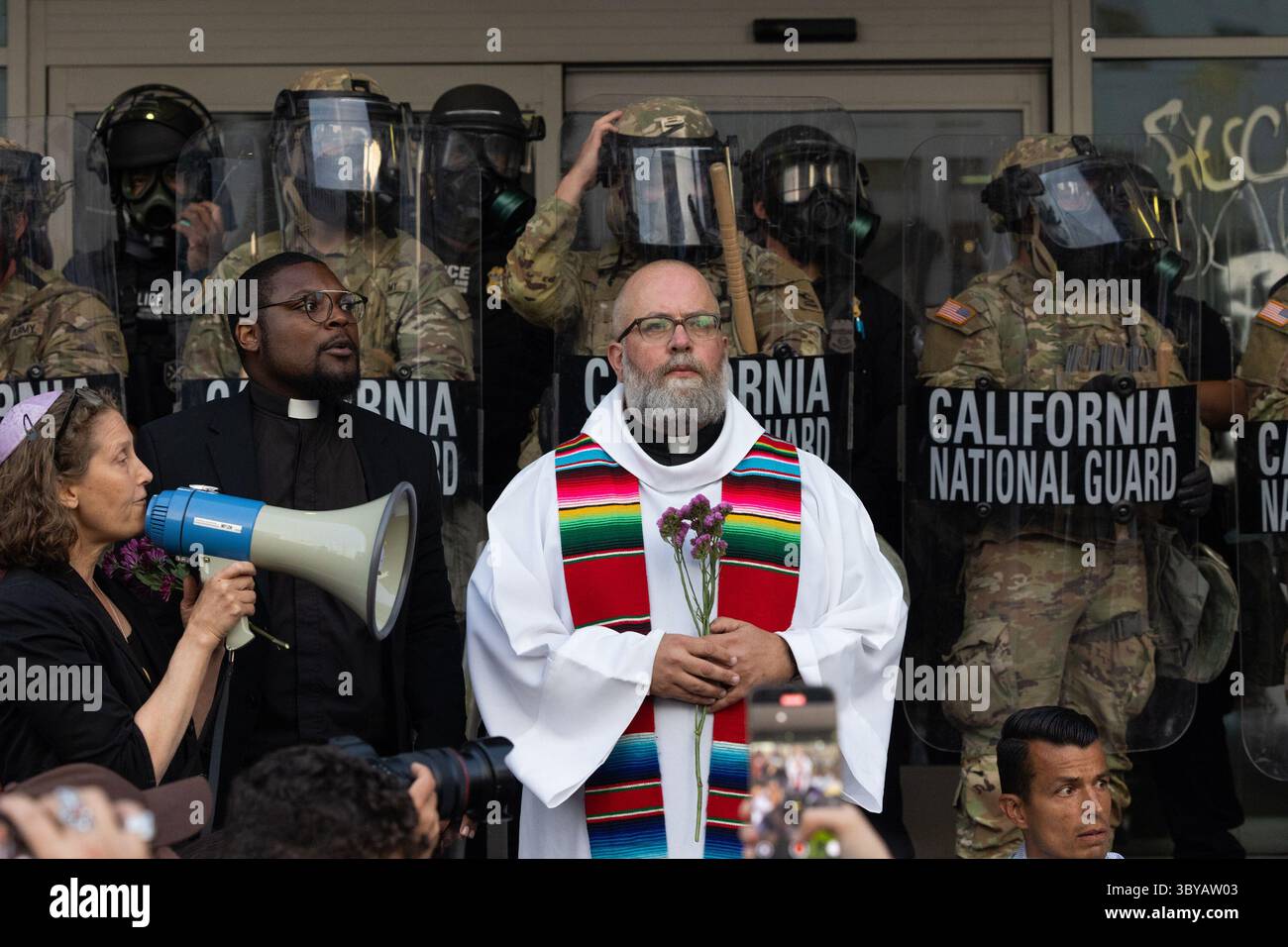 Los Angeles, Kalifornien, USA. Juni 2025. Pater Brendan Busse schließt sich den Geistlichen VON LA während eines ICE-Einwanderungsprotests an, als Mitglieder der California National Guard am 10. Juni 2025 eine Perimeter am Los Angeles Street Federal Building in Los Angeles, CA, halten. (Credit Image: © Jonathan Alcorn/ZUMA Press Wire) NUR REDAKTIONELLE VERWENDUNG! Nicht für kommerzielle ZWECKE! Stockfoto