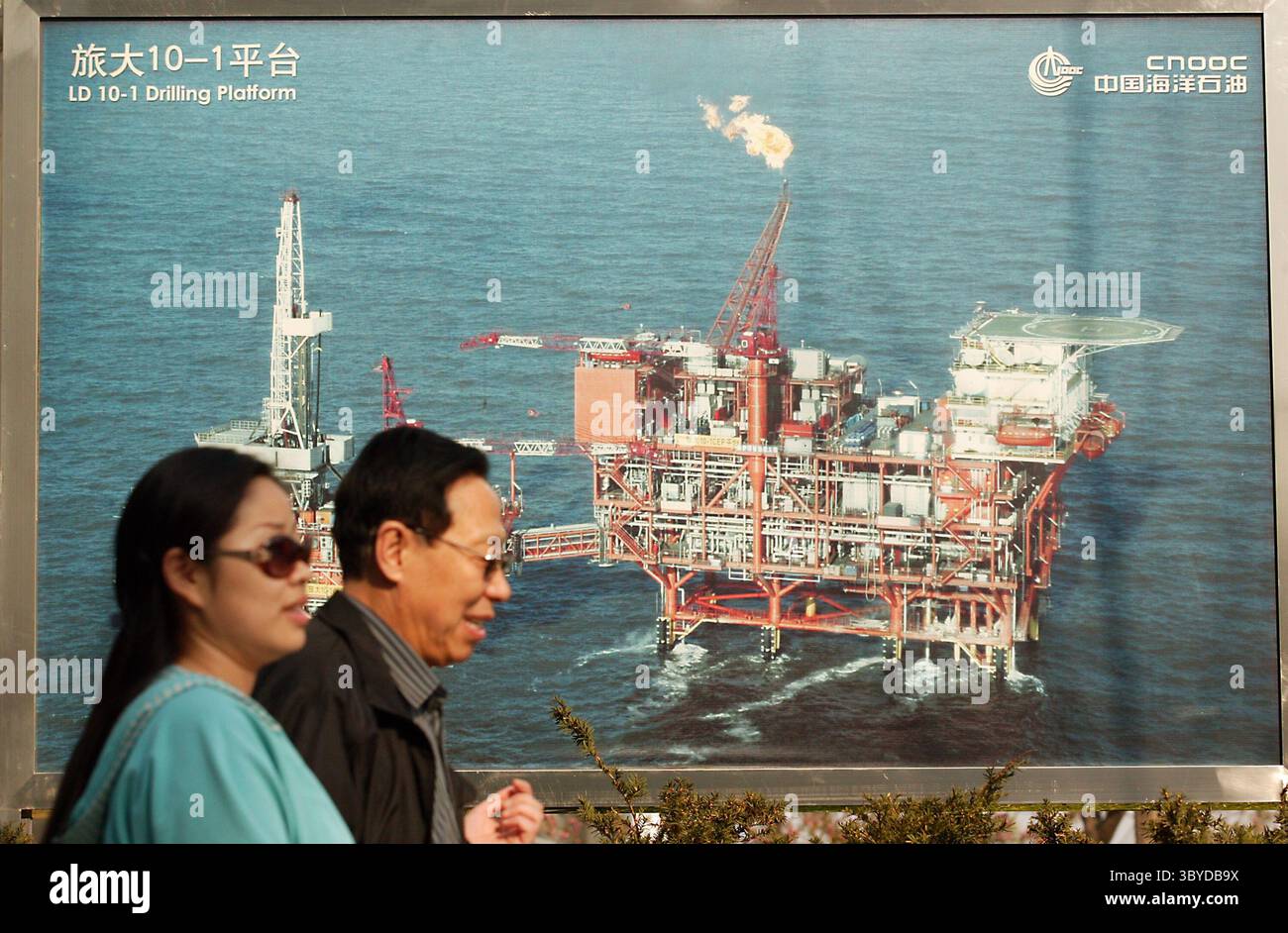 8. April 2009, PEKING, CHINA: Chinesen spazieren vorbei an einem Foto einer Ölbohrplattform vor dem Hauptquartier einer der drei größten chinesischen Ölgesellschaften in der Innenstadt von Peking am 8. April 2009. Das Wachstum der Ölnachfrage in China, dem zweitgrößten Energienutzer der worldâ, wird durch hohe Preise gebremst werden, da die Verbraucher auf steigende Kosten reagieren, sagte ein rangiger Ökonom bei Australiaâ größten Kreditgeber nach Marktwert. (Bild: © Stephen Shaver/ZUMA Press Wire) Stockfoto