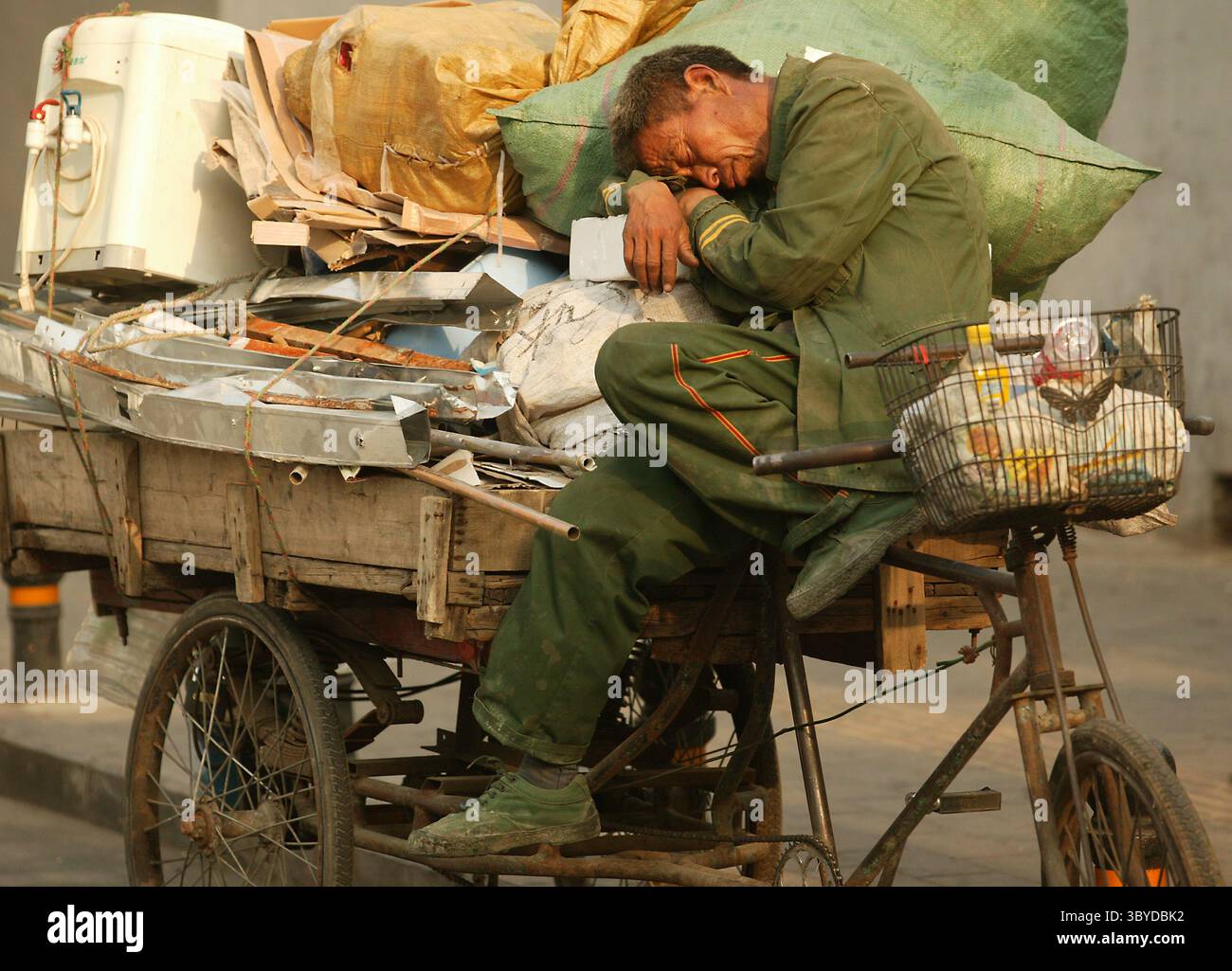 14. Mai 2009, PEKING, CHINA: Ein chinesischer Migrant, der recycelbaren Müll sammelt, macht am 14. Mai 2009 in Peking ein Nickerchen auf seinem „Flachbett“-Dreirad. Während China nach Jahren des umweltschädlichen Wachstums Dutzende Milliarden in die Sanierung investiert, kämpfen große und kleine Unternehmen um Verträge, um verschmutzte Wasserstraßen und Deponien wiederherzustellen. (Bild: © Stephen Shaver/ZUMA Press Wire) Stockfoto