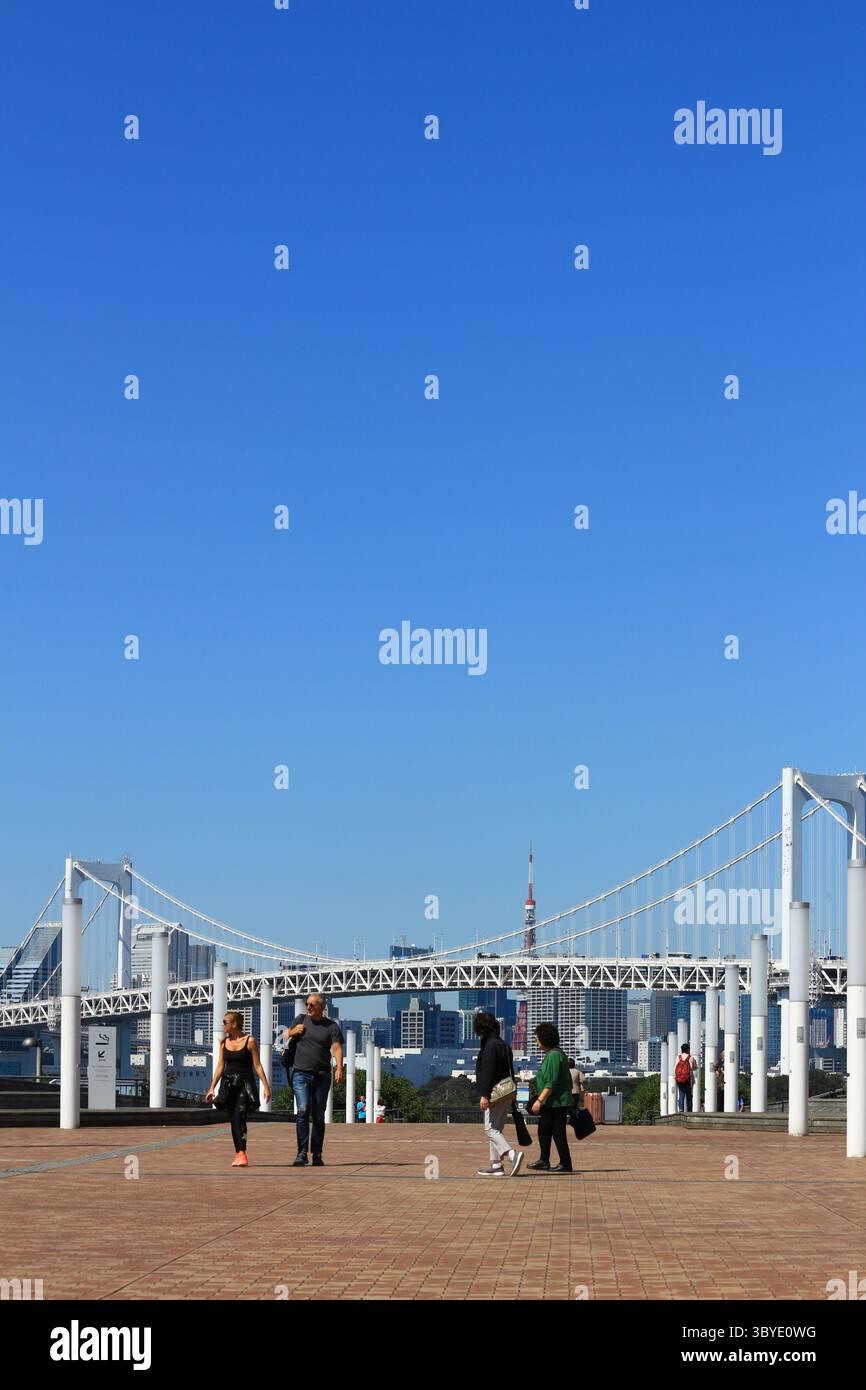 Das tägliche Leben in Japan Odaiba Promenade mit Blick auf den Tokyo Tower und die Tokyo Rainbow Bridge, mit Touristen, die kommen und gehen Stockfoto