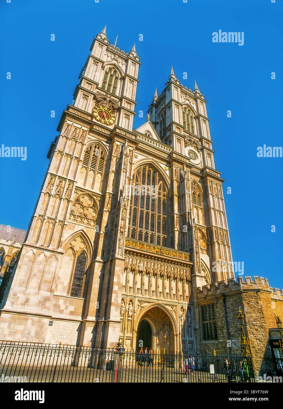 Der große Eingang der Westminster Abbey mit Doppeltürmen und raffiniertem gotischem Design, der unter hellem Sonnenlicht erfasst wird Stockfoto