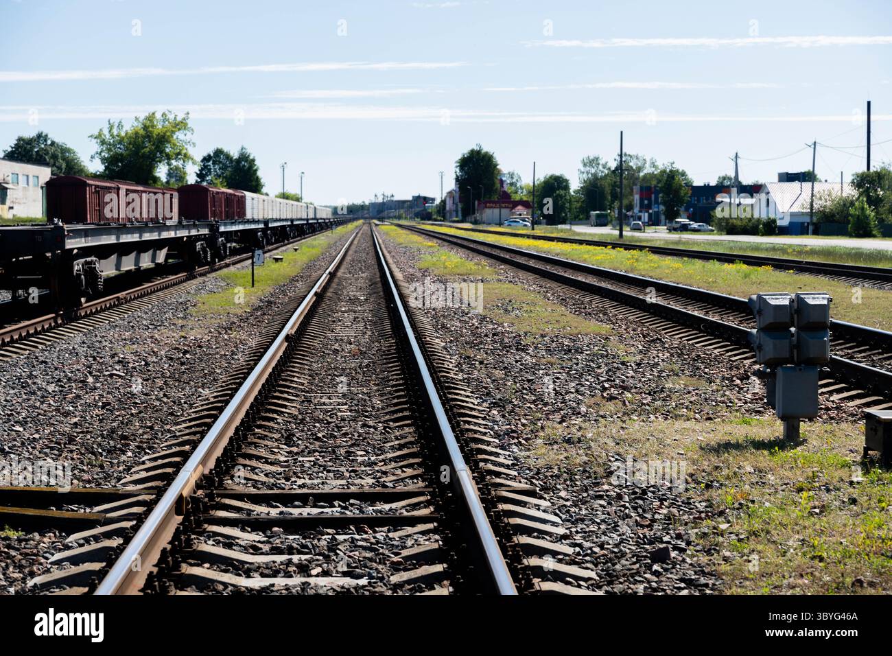Ein atemberaubender Blick aus der Luft auf die weitläufigen Eisenbahnschienen, die sich unter einem hellblauen Himmel in die Ferne erstrecken. Flauschige Wolken verleihen der Szene Tiefe, während Stockfoto