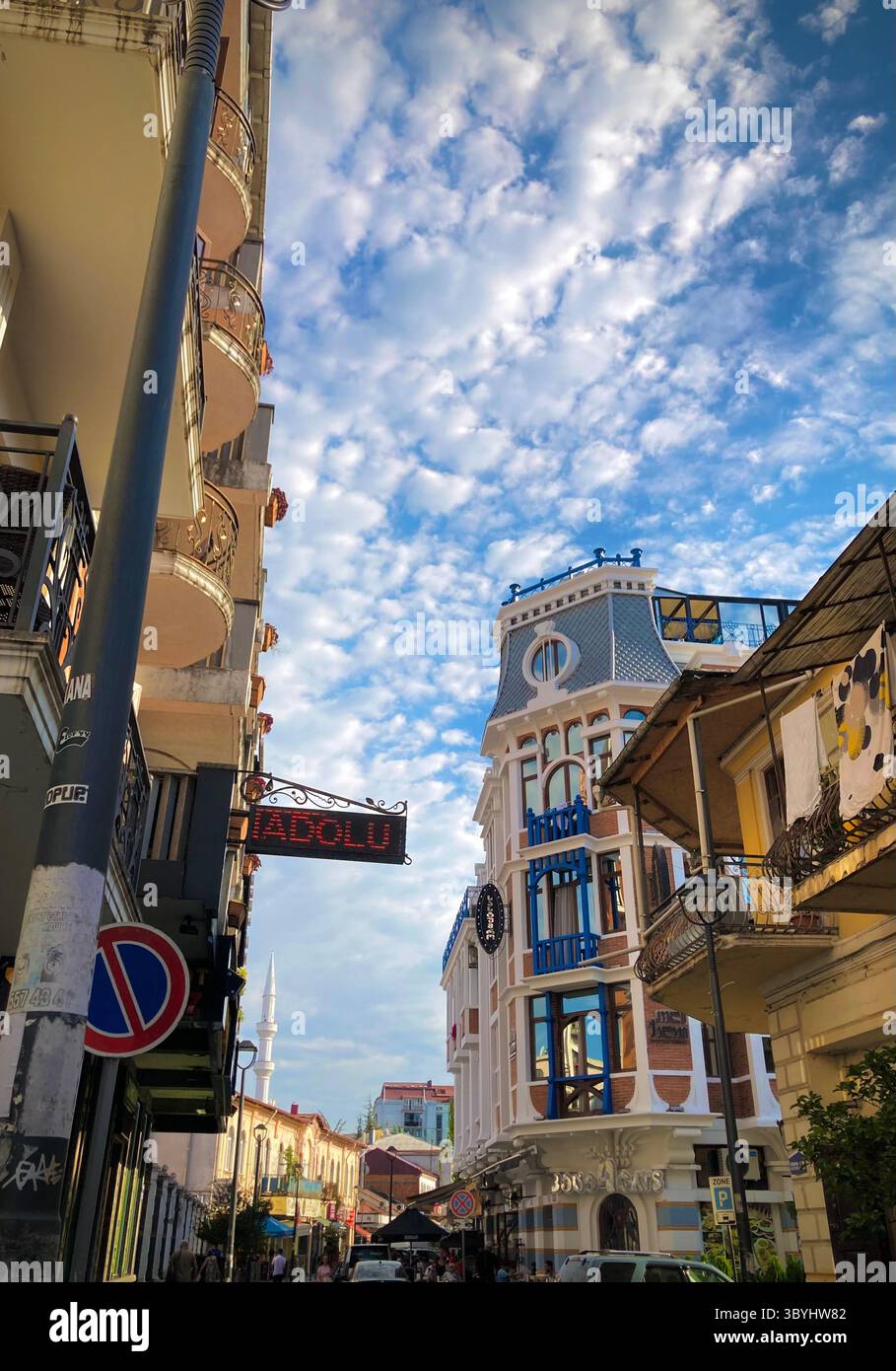 Charmante urbane Straße in Batumi, Georgia, mit einer Mischung aus traditioneller und moderner Architektur. Im Hintergrund erhebt sich ein Moscheeminarett. Stockfoto