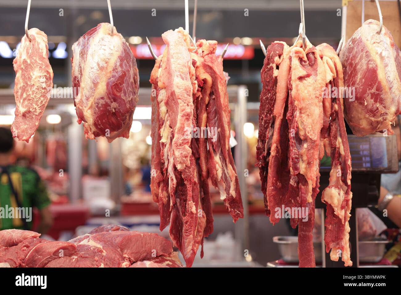 Verschiedene Rindfleischstücke werden an Haken gehängt. Es werden verschiedene Rindfleischstücke angezeigt, die den Kunden zur Auswahl stehen. Stockfoto