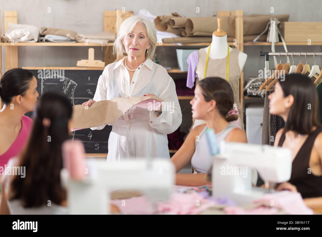 Reife Lehrerin, die zeigt, wie man ein Kleid macht Stockfoto