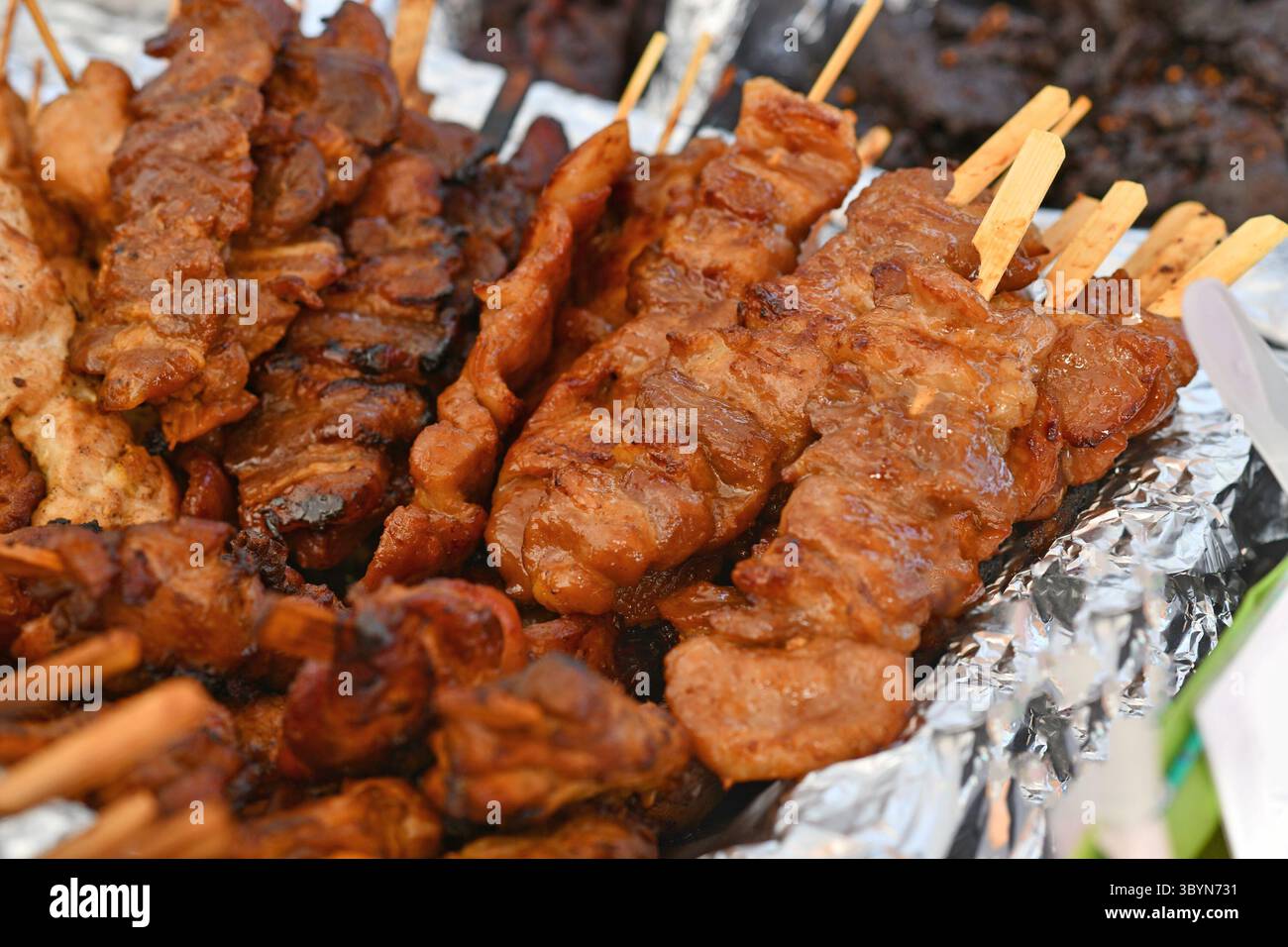 Gegrilltes Schweinefleisch-Barbecue beim Thai Street Food Festival. Traditionelle thailändische Spieße werden auf dem Markt im Freien serviert Stockfoto