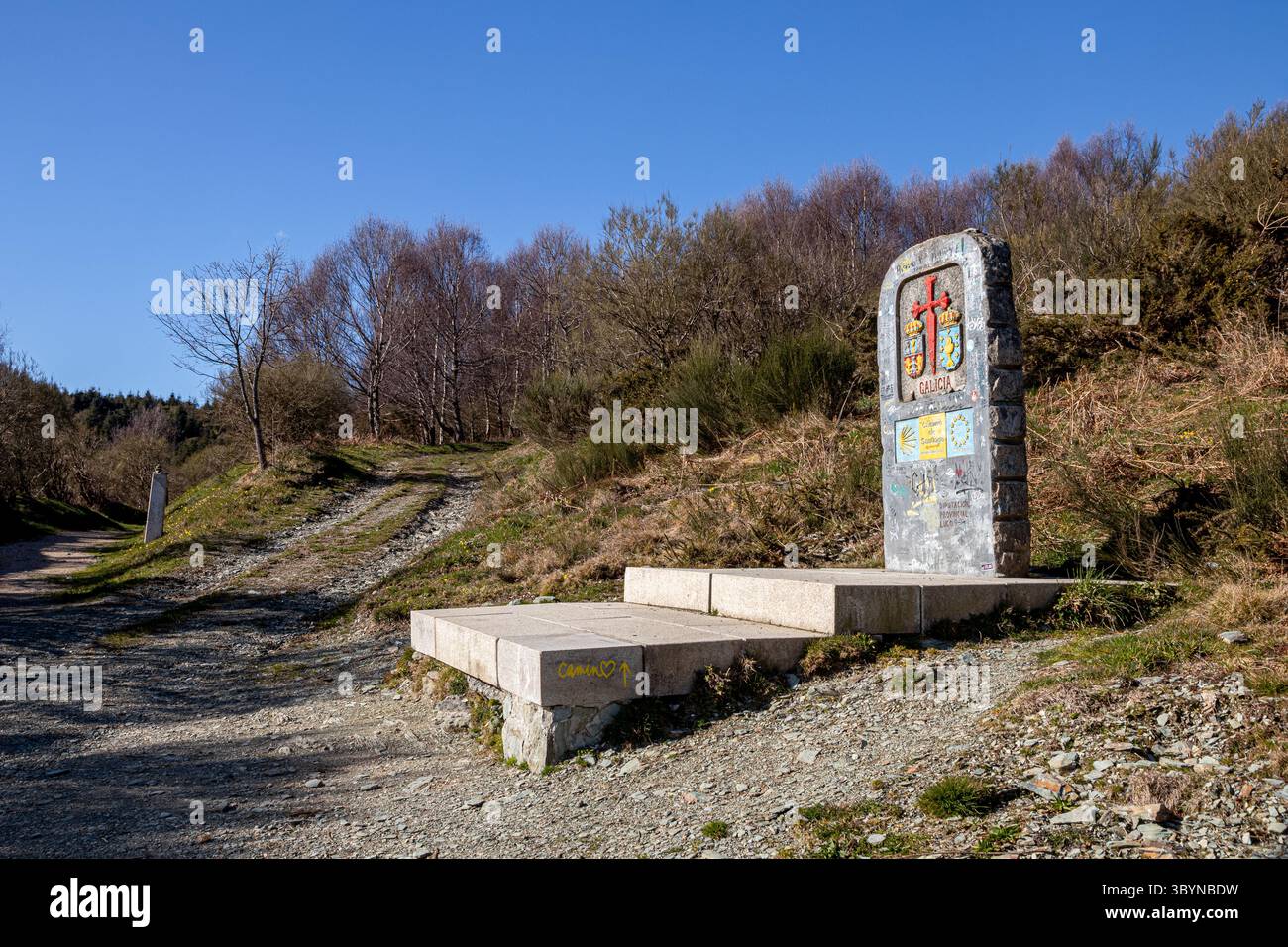 O Cebreiro, Spanien. Monolith markiert die Grenze zwischen Castilla y Leon und Galicien mit rotem Santiago-Kreuz, Graffiti- und Pilgersignaturen, Jakobsmuscheln Stockfoto