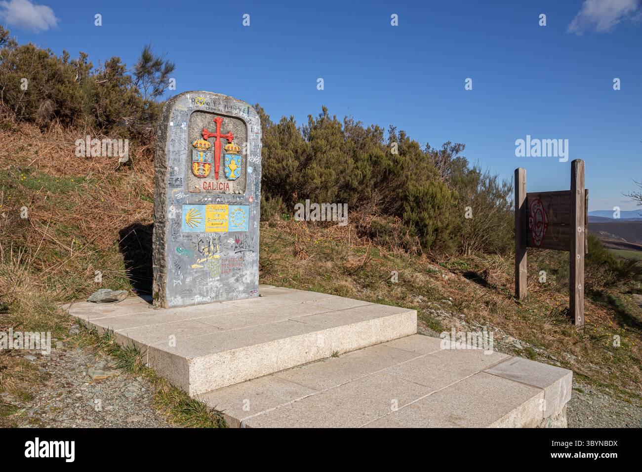 O Cebreiro, Spanien. Monolith markiert die Grenze zwischen Castilla y Leon und Galicien mit rotem Santiago-Kreuz, Graffiti- und Pilgersignaturen, Jakobsmuscheln Stockfoto