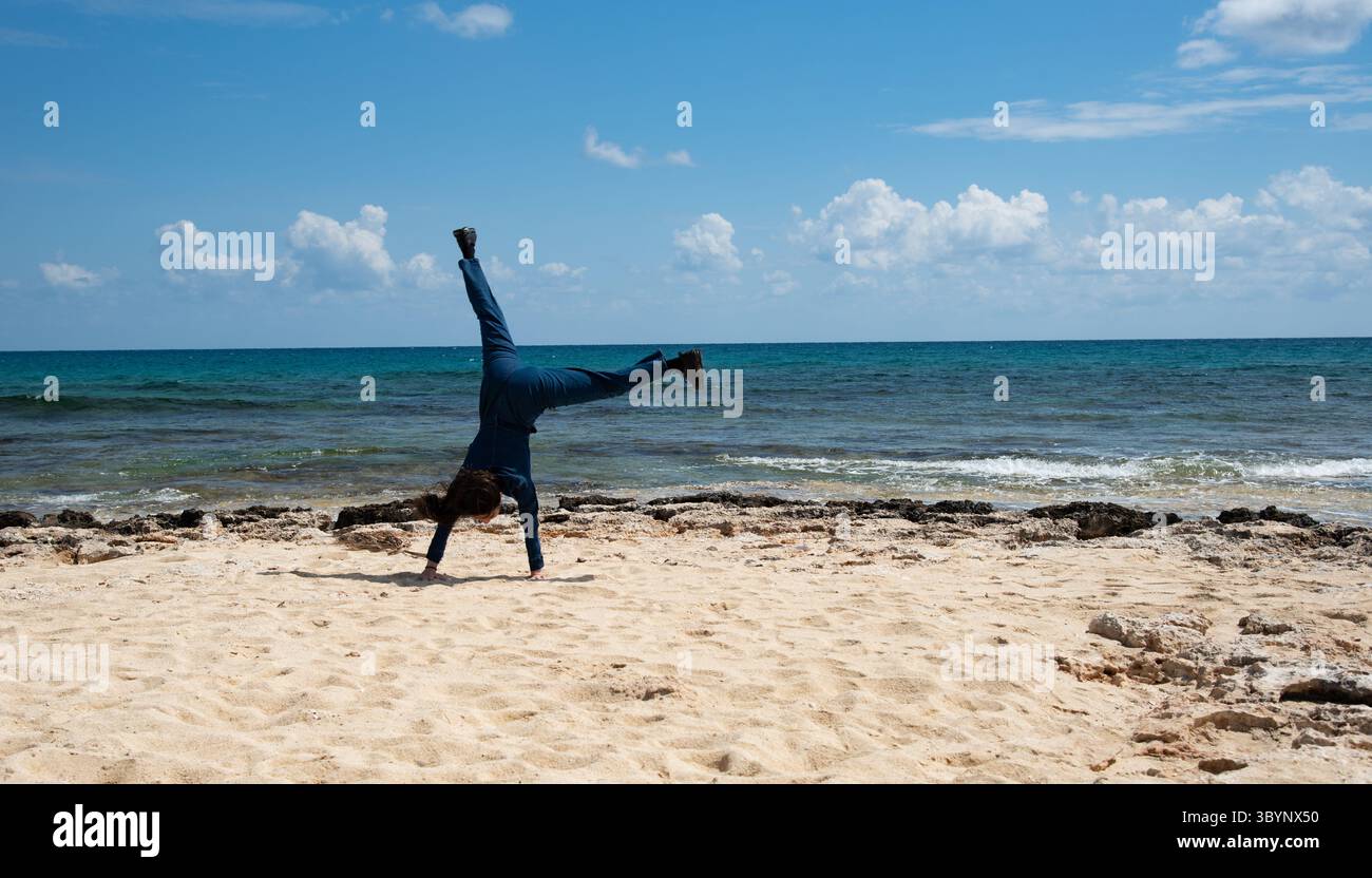 Frau, die an einem wunderschönen Strand ein Rad spielt, die Work-Life-Balance genießt und Erfolg feiert Stockfoto