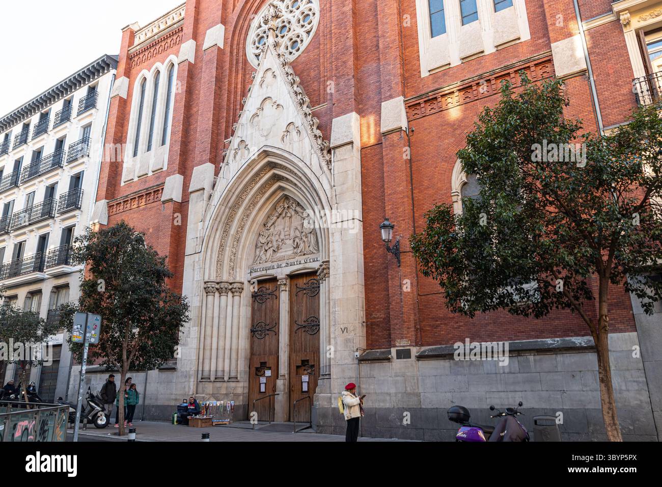 Madrid, Spanien. Kirche Santa Cruz in Atocha 6 aus neogotischen Backsteinen und weißem Stein, mit spitzem Bogeneingang, Rosenfenster und einem hohen Turm, der sich darüber erhebt Stockfoto