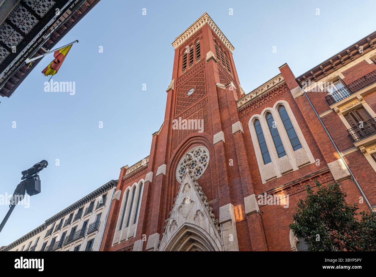 Madrid, Spanien. Kirche Santa Cruz in Atocha 6 aus neogotischen Backsteinen und weißem Stein, mit spitzem Bogeneingang, Rosenfenster und einem hohen Turm, der sich darüber erhebt Stockfoto