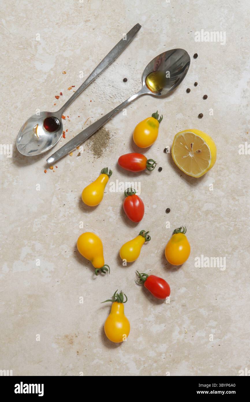Zutaten für Sommersalat - frisch geerntete Kirschtomaten, Löffel Essig und Olivenöl, Salz und Pfeffer Stockfoto