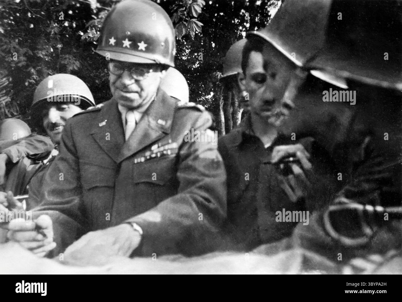 1944 Momentaufnahme des US-amerikanischen Generals Omar Bradley, der Dokumente mit US-Soldaten in der Normandie unterzeichnete. Stockfoto