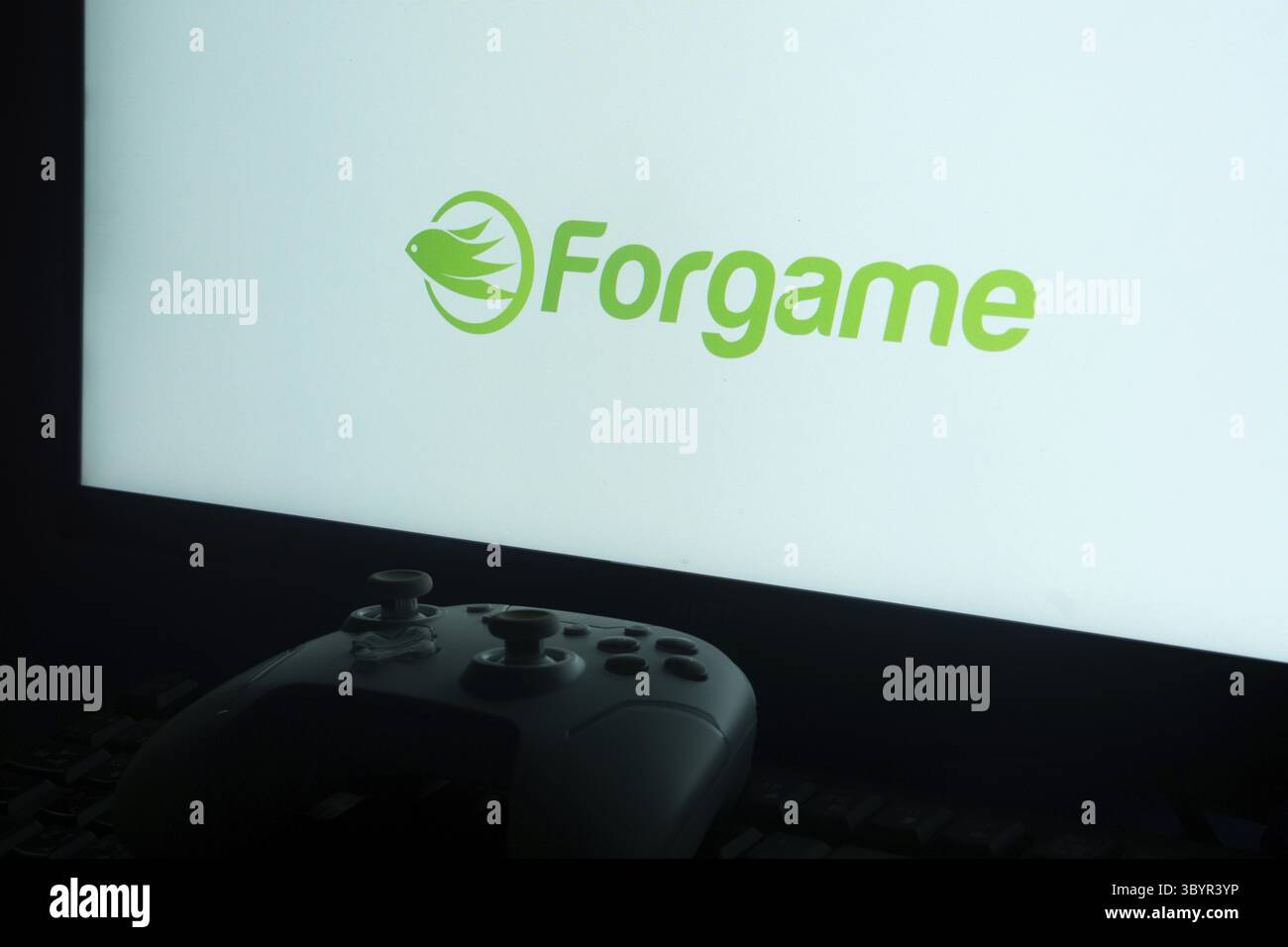 Controller vor einem hellen Bildschirm mit dem Forgame-Logo für eine Gaming-Atmosphäre Stockfoto
