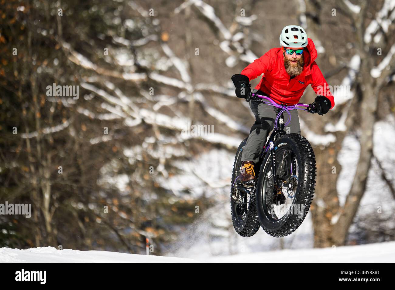 Radfahrer springt Fat Bike im Schnee während des Montpelier, VT, Winterfest Fat Bike Rennen. Stockfoto
