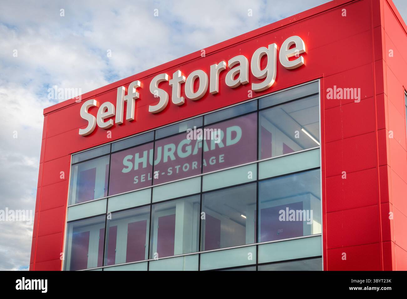 Rote Glasfassade einer Shurgard-Selbstlagereinrichtung/-Einheit vor blauem Himmel in England, Großbritannien Southampton, England, Großbritannien Stockfoto