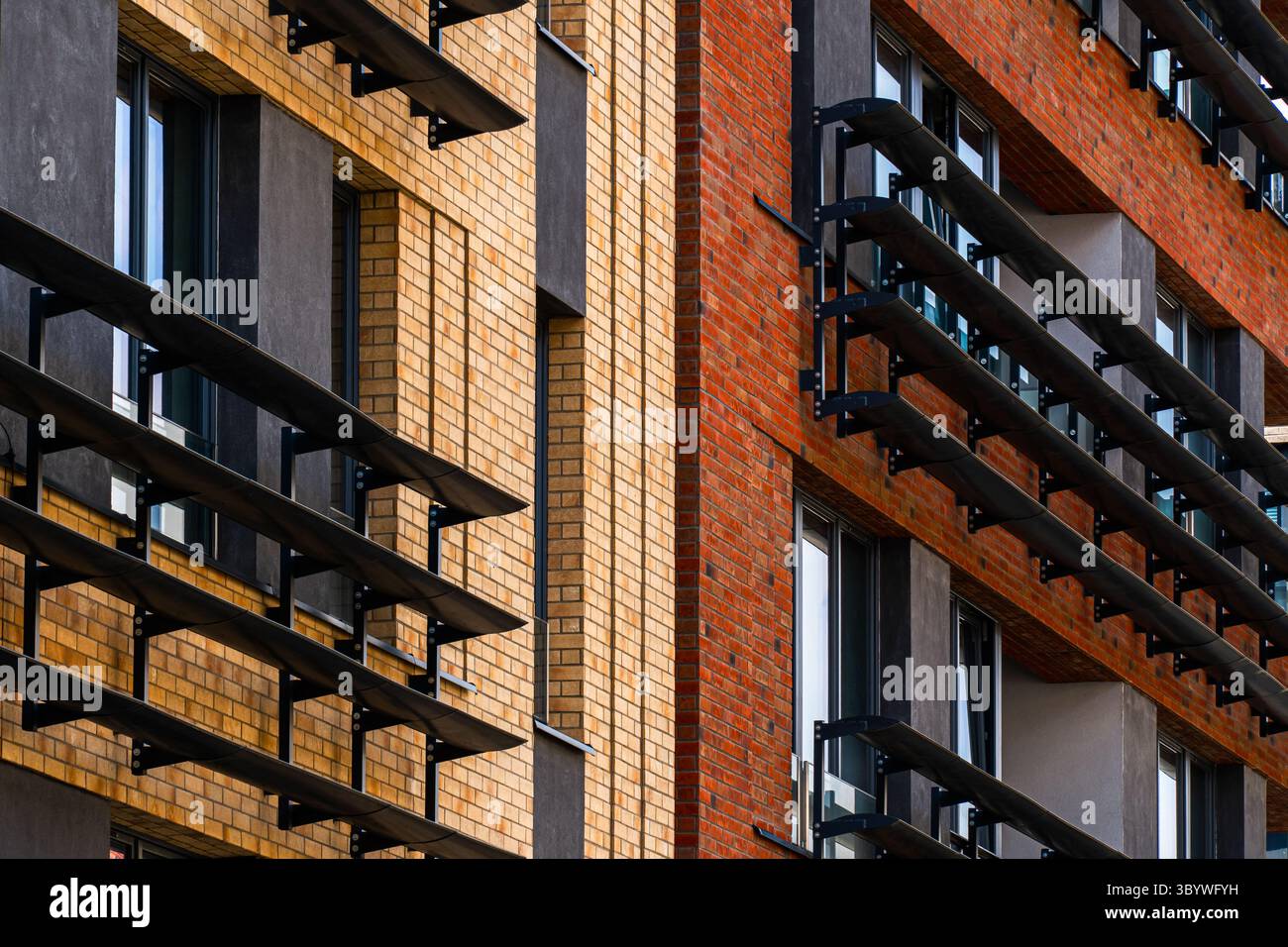 Modernes Backsteingebäude mit schwarzen Metallbalkonen und Fenstern Stockfoto