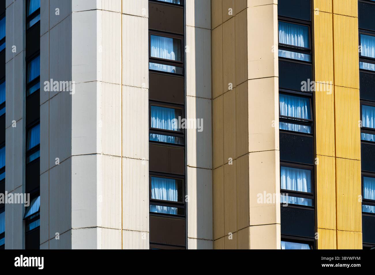 Moderner Hochbau mit strukturierten vertikalen Panels und reflektierenden Fensterbändern Stockfoto