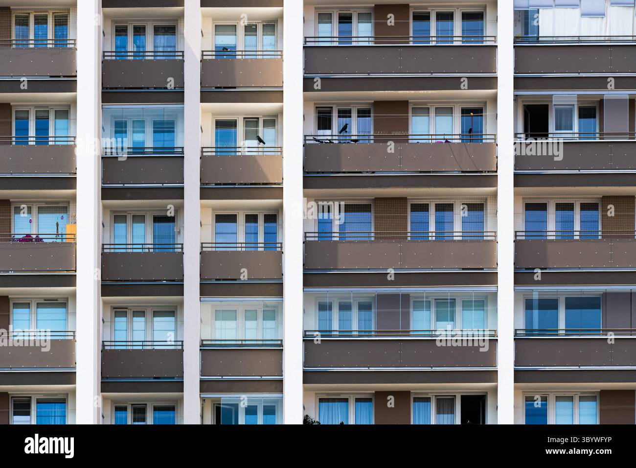 Symmetrische Apartmentfassade mit braunen Paneelen und sich wiederholenden Balkonen Stockfoto