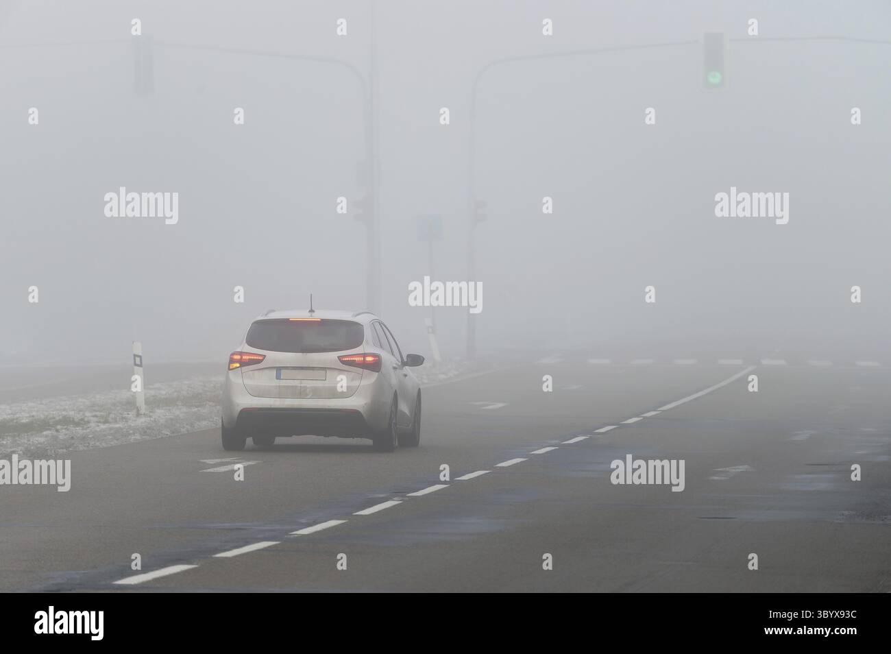 Autos im Nebel. Schlechtes Winterwetter und gefährlicher Autoverkehr auf der Straße. Leichte Fahrzeuge im Nebel Stockfoto