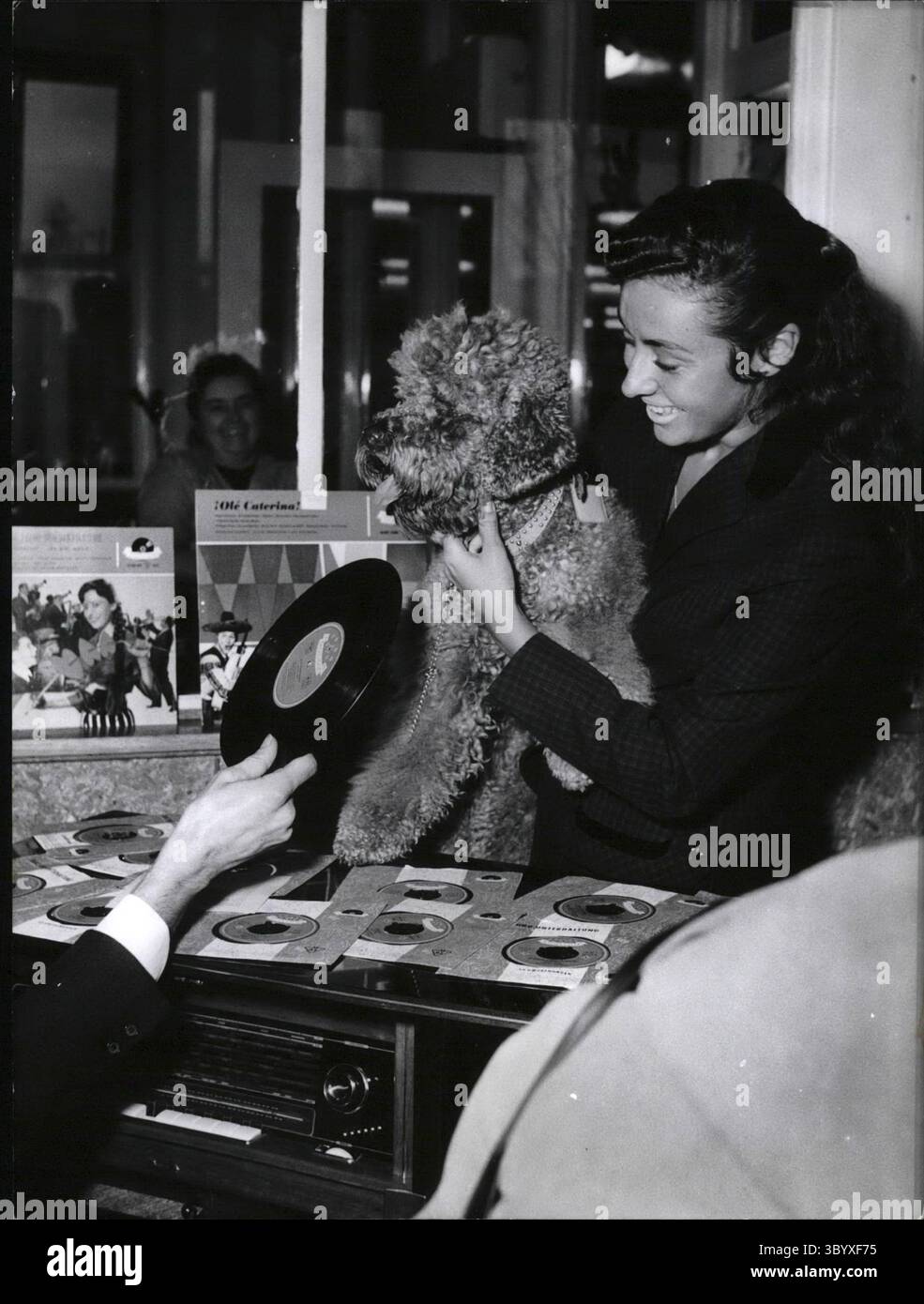 15. Dezember 1956 - die brasilianische Oscar-Platte für die Sängerin Caterine Valente kehrte von einer sehr erfolgreichen Amerika-Tour zurück und traf die berühmte Sängerin Caterine Valente am Frankfurter Flughafen ein. Dort wurde sie von einer Menge Fans begrüßt. In den Speisesälen des Frankfurter Flughafens wurde eine Musikbox installiert, in der alle großen Hits von Caterine Valente aufgenommen wurden. Während ihrer Amerika-Tour erhielt Caterine Valente den Preis des besten ausländischen Sängers der brasilianischen Zeitung O Globo mit dem Namen Record Oscar. OPS: Die berühmte Sängerin Caterine Valente bei ihrer Ankunft in Frankfurt, mit ihrem schwarzen Pudel und einer ihrer neuesten Aufnahmen. (C Stockfoto