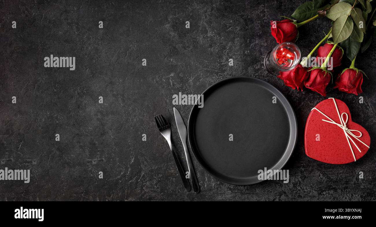 Sankt Valentinstag Konzept. Feier-Dinner mit Bouquet von roten Rosen, Herd saheped Geschenkbox und Champagner-Glas auf dem schwarzen Stein Tisch mit c Stockfoto