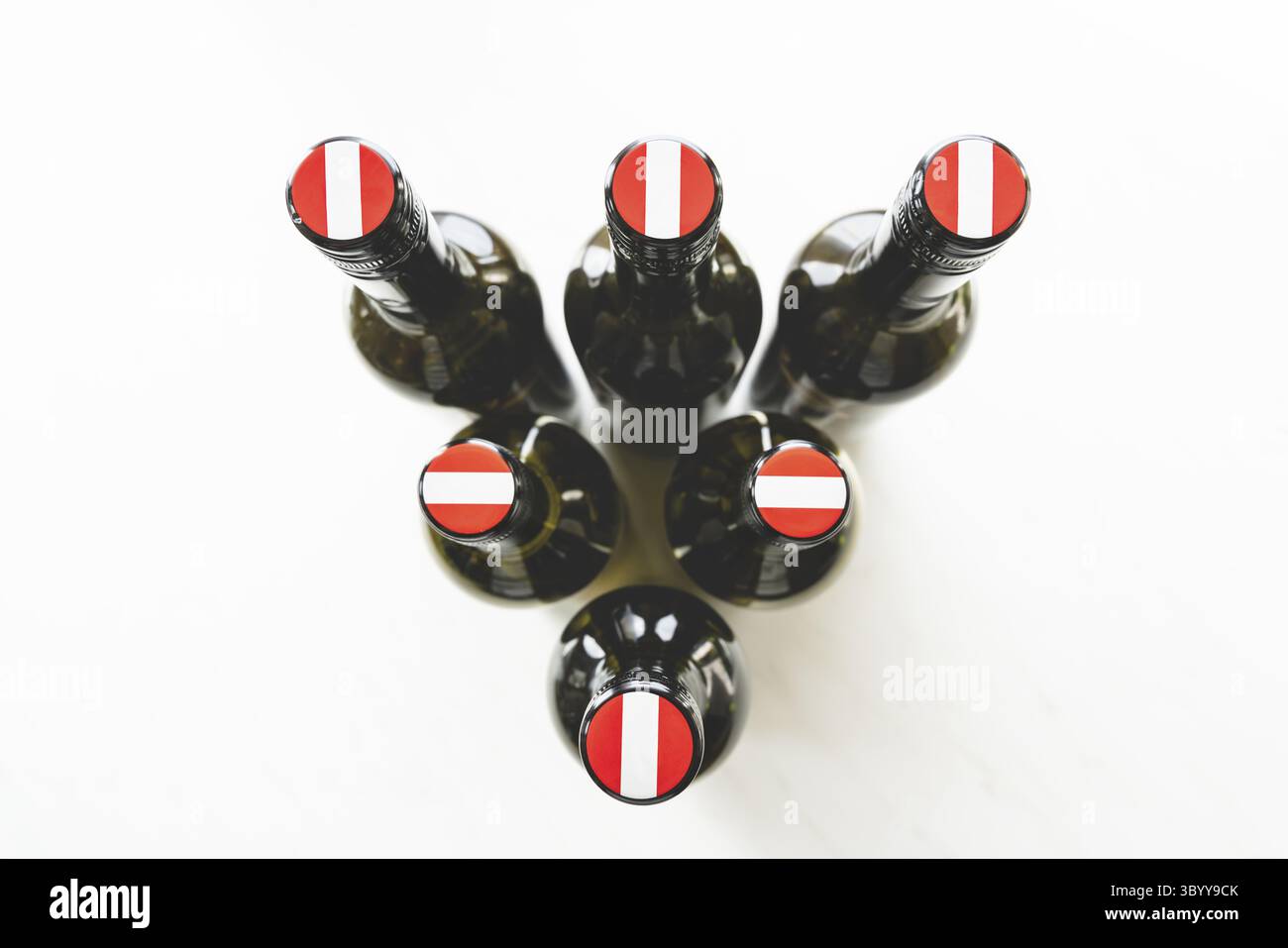 Weinflaschen mit österreichischen Flaggen auf den Schraubverschlüssen von Die Oberseite in einem Dreieck in hellem Licht angeordnet Stockfoto