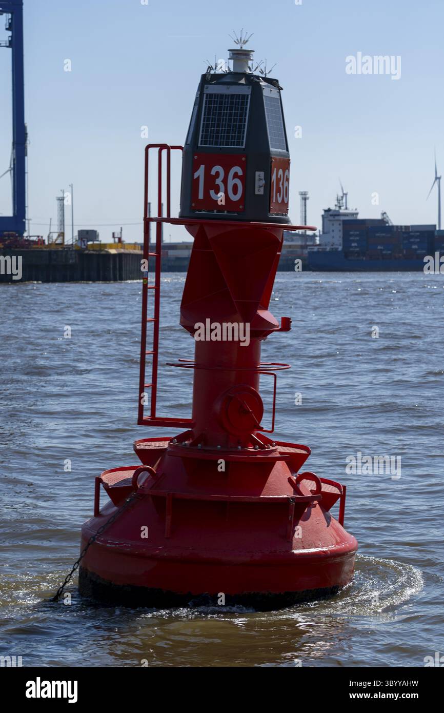Rote Fahrwasserboje mit der Markierung 136 schwimmend auf der Elbe, ausgestattet mit Solarpanel und Leuchtfeuer für die Navigation, in den Hinterteilen des Containers Stockfoto