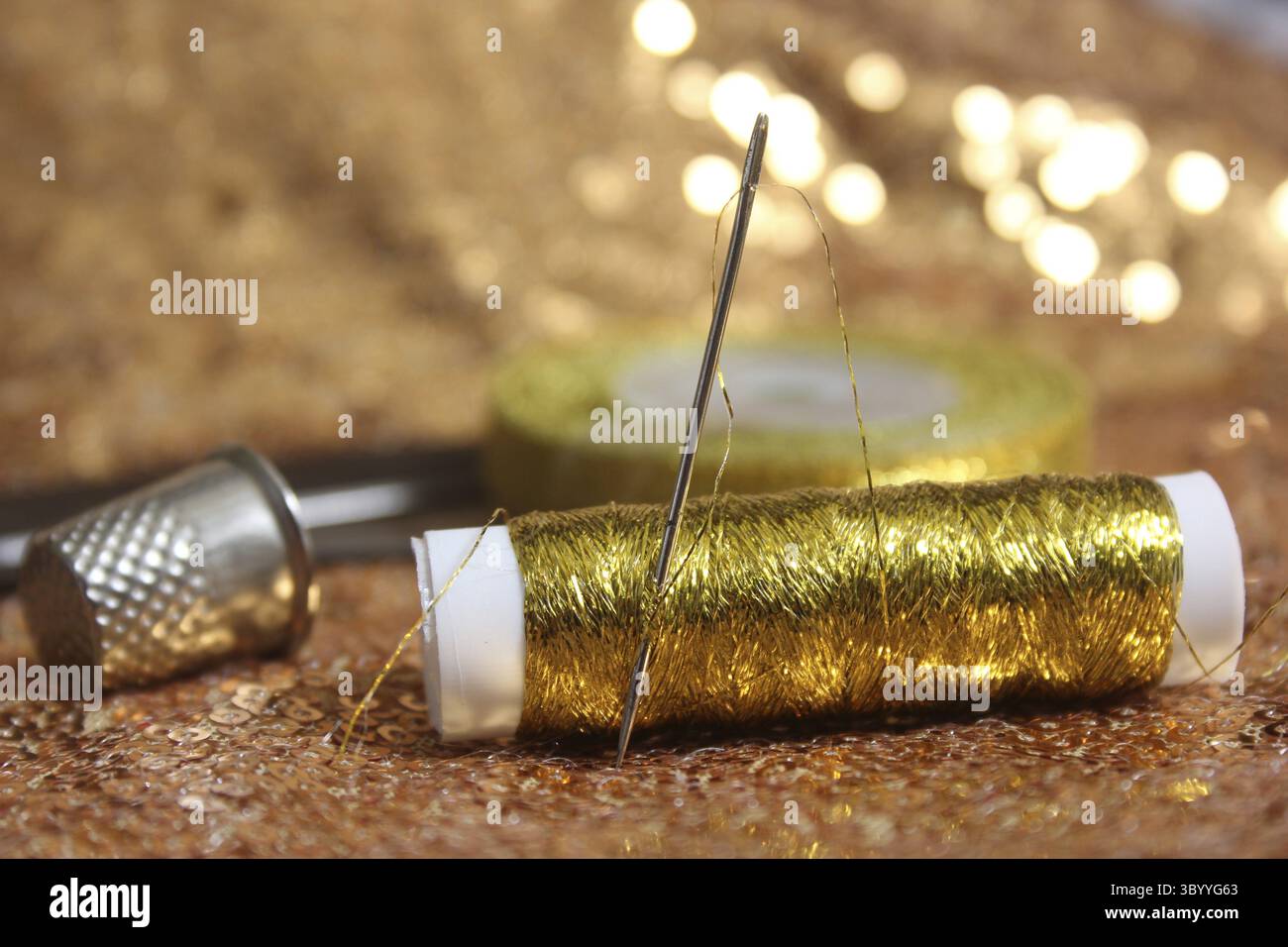 Goldene Pailletten auf Stoff mit goldfarbenem metallischem Gewinde und Kaugummi Stockfoto