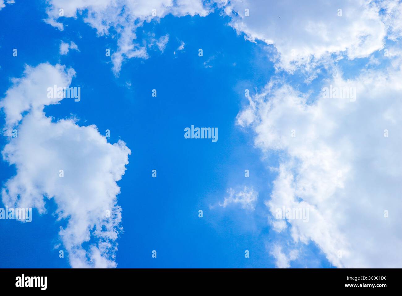 Blauer tropischer Himmel mit flauschigen Wolken und Sonnenlicht, durch das gefiltert wird. Ideal für den Einsatz in Hintergrundszenen, Wetterthemen oder Konzepten der natürlichen Ruhe. Stockfoto