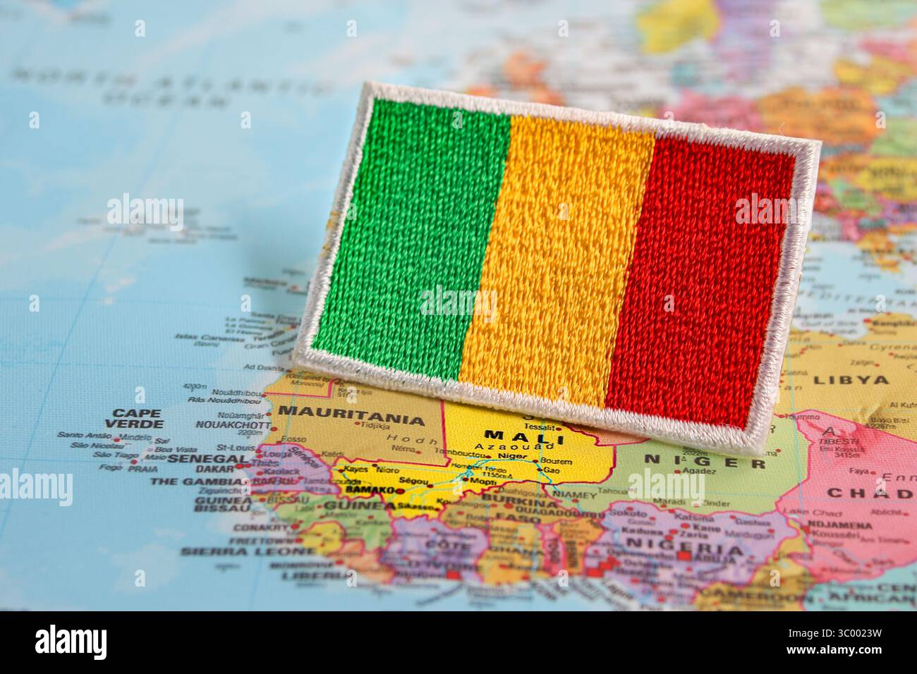 Umweltfreundliche Mali-Flagge mit Garn und Tuch auf einer Weltkarte, die Mali in Westafrika hervorhebt. Reise- und Nachhaltigkeitskonzept. Stockfoto
