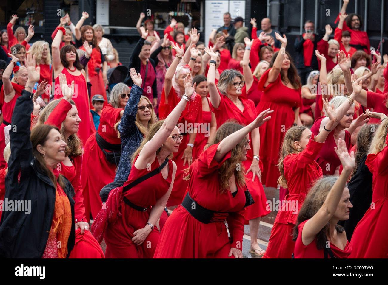 Folkestone, Großbritannien. Juli 2025. Die Fans üben die Choreographie vor der Vorstellung am Folkestone Pier. Hunderte von Kate Bush Fans versammelten sich in roten Kleidern am Folkestone Pier, um den Most Wuthering Heights Day oder den Kate Bush Day mit Tanz zu feiern. Quelle: SOPA Images Limited/Alamy Live News Stockfoto