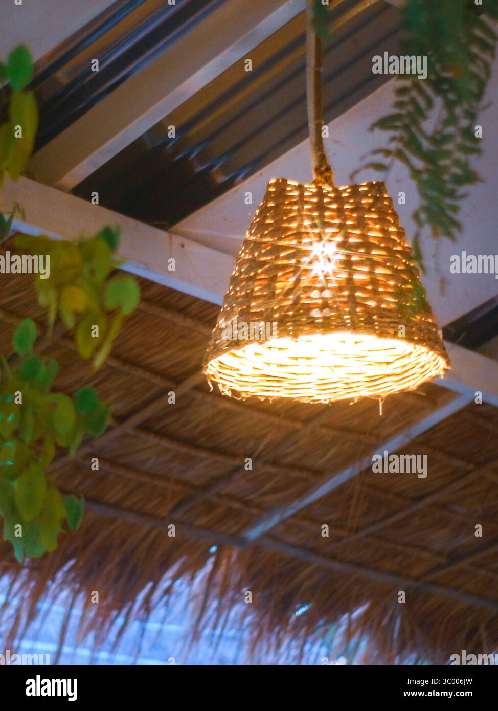 ECO Bambus Korbleuchte leuchtet in ländlichen Räumen, zeigt natürliche Materialien und nachhaltige rustikale Einrichtung in Boho-inspirierter Inneneinrichtung. Stockfoto