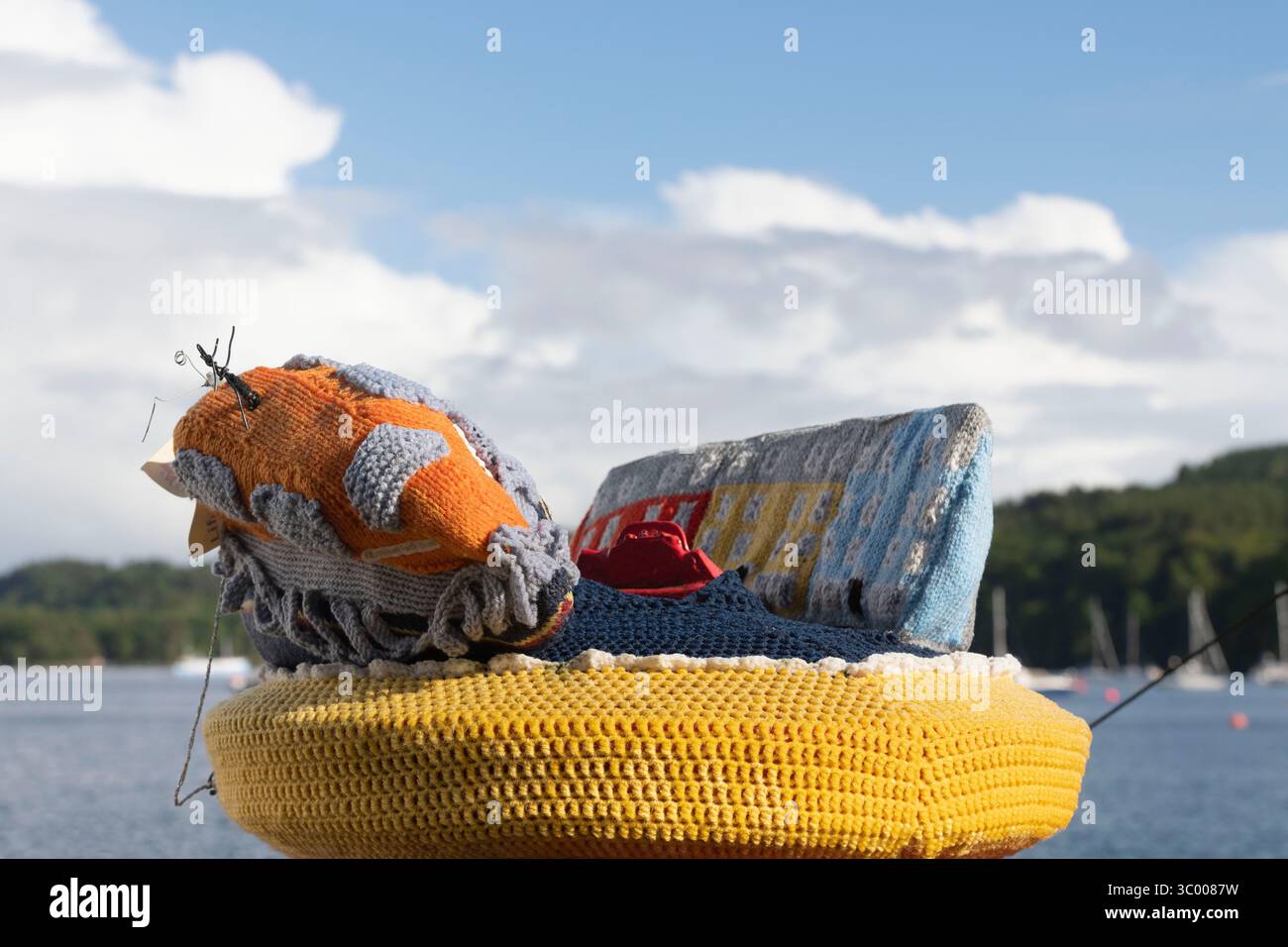 Ein gehäkelter Briefkasten-Topper an der Waterfront von Tobermory, der das RNLI Lifeboat, einen Red Lobster und die berühmte Reihe farbenfroher Gebäude zeigt Stockfoto