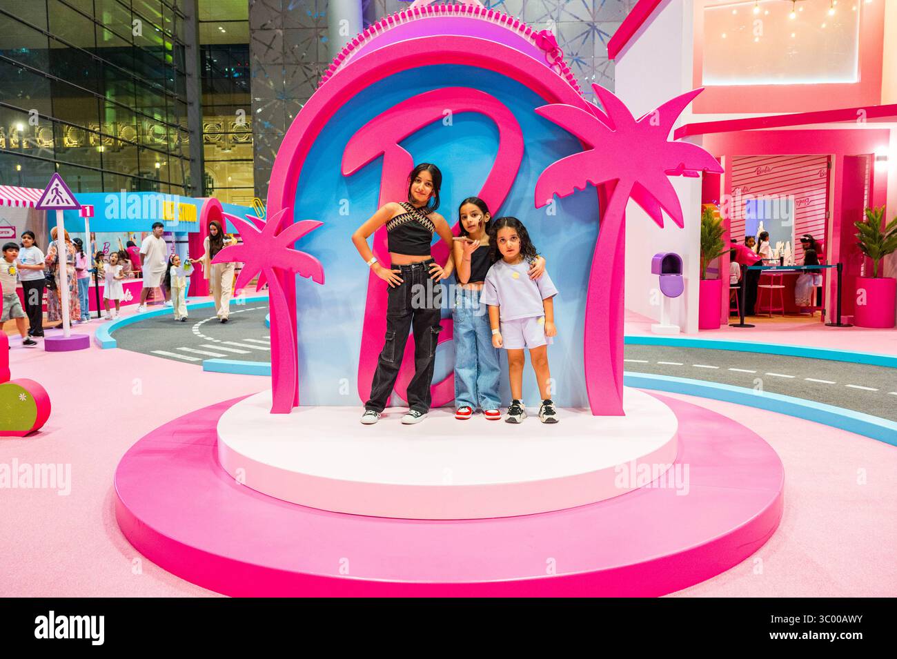 QATAR TOY FESTIVAL IN DOHA drei Mädchen posieren für ein Foto vor dem Barbie Pavillon beim Qatar Toy Festival im Doha Exhibition and Convention Center DECC i Stockfoto
